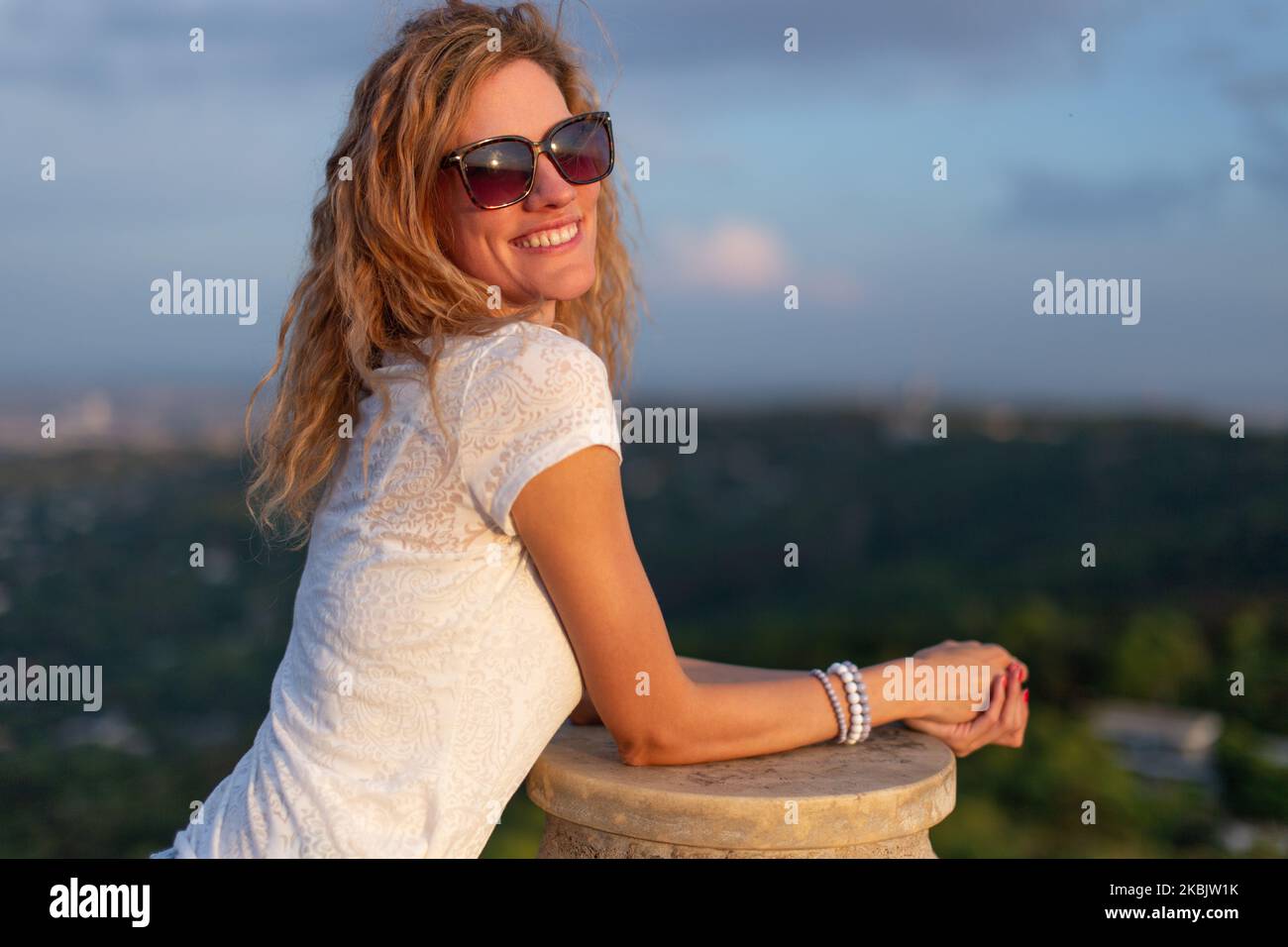 Junge ausgeglichene kaukasische Frau in Sonnenbrillen, die den Sonnenuntergang im Freien genießen Stockfoto