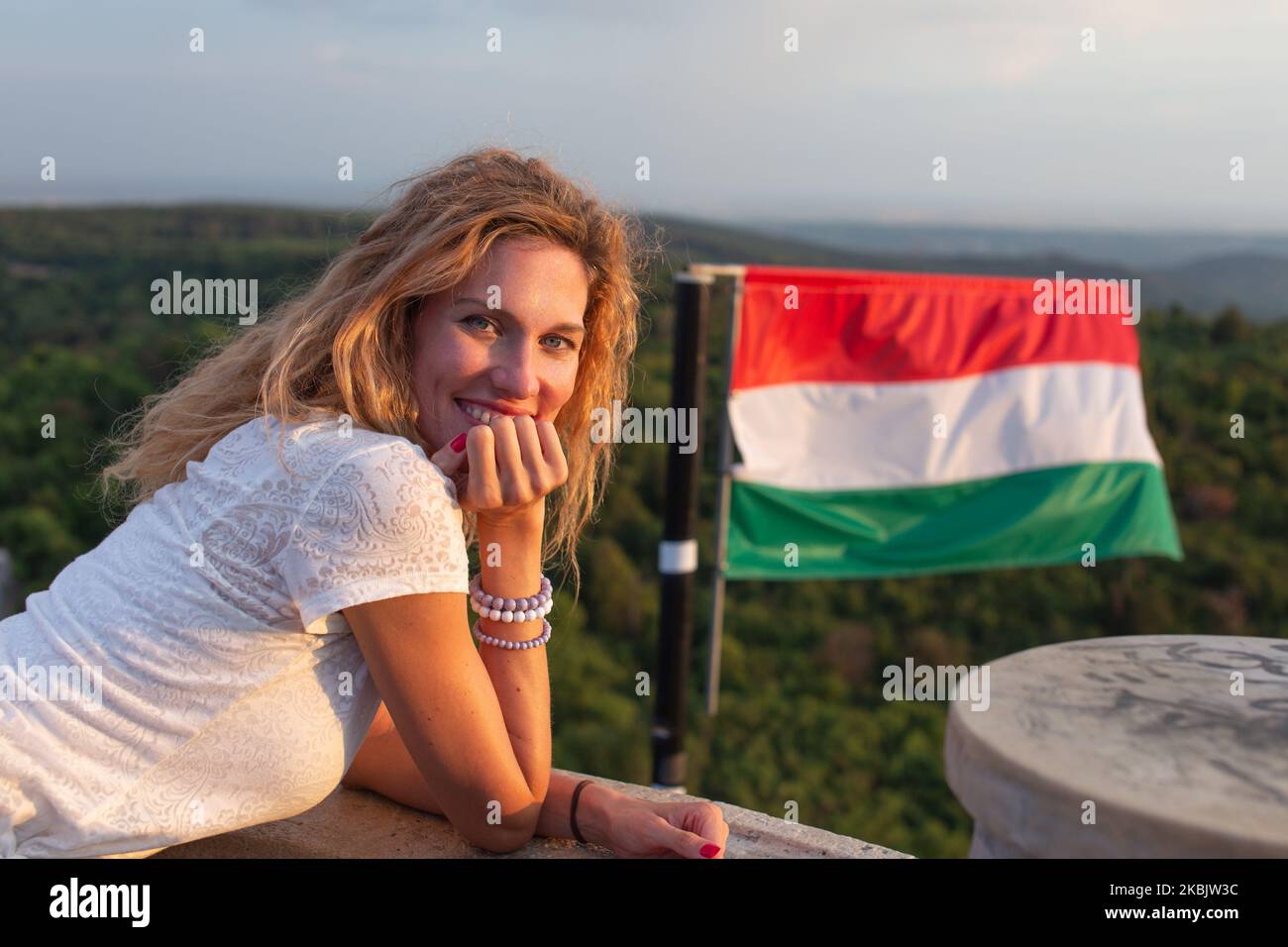 Junge verspielte kaukasische Frau, die sich in der Natur bei der ungarischen Flagge, Ungarn, entspannt Stockfoto