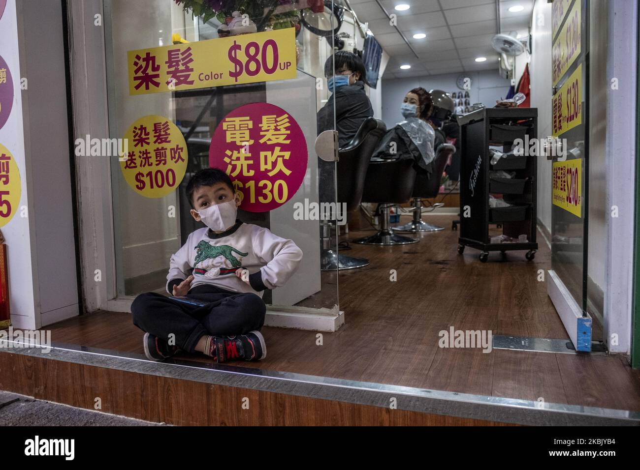 Ein Junge mit einer Maske sitzt am 13. März 2020 vor einem Friseurladen in Hongkong, China. Das Coronavirus oder Covid-19, das aus Wuhan China stammt, hat über 120.000 infiziert und weltweit 4617 getötet. Die Weltgesundheitsorganisation (WHO) hat das Covid-19 als Ausbruch erklärt. (Foto von Vernon Yuen/NurPhoto) Stockfoto