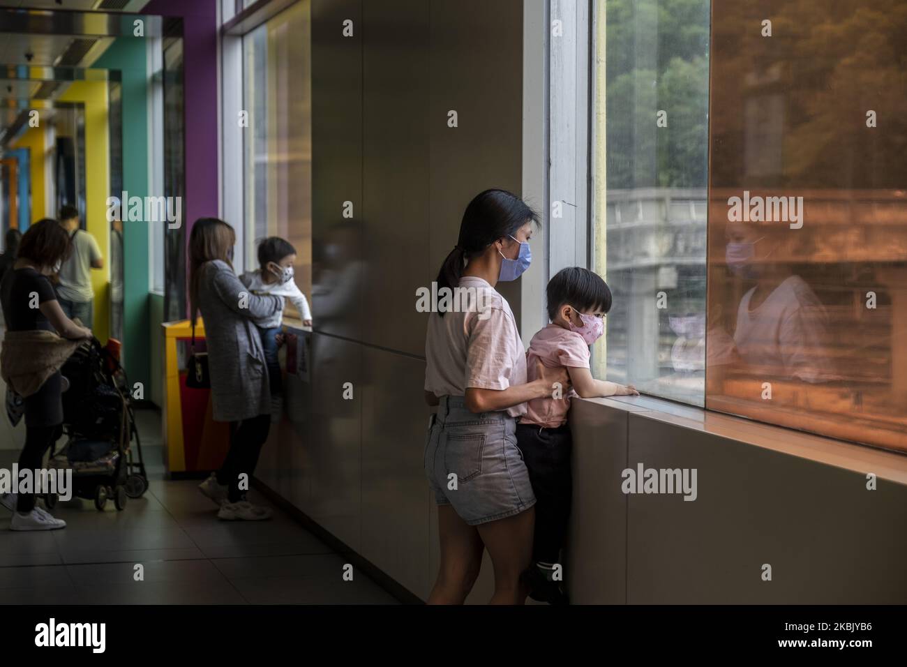 Eine Frau hält einen Jungen, der eine Maske trägt, während er am 13. März 2020 in Hongkong, China, aus einem Fenster schaut. Das Coronavirus oder Covid-19, das aus Wuhan China stammt, hat über 120.000 infiziert und weltweit 4617 getötet. Die Weltgesundheitsorganisation (WHO) hat das Covid-19 als Ausbruch erklärt. (Foto von Vernon Yuen/NurPhoto) Stockfoto