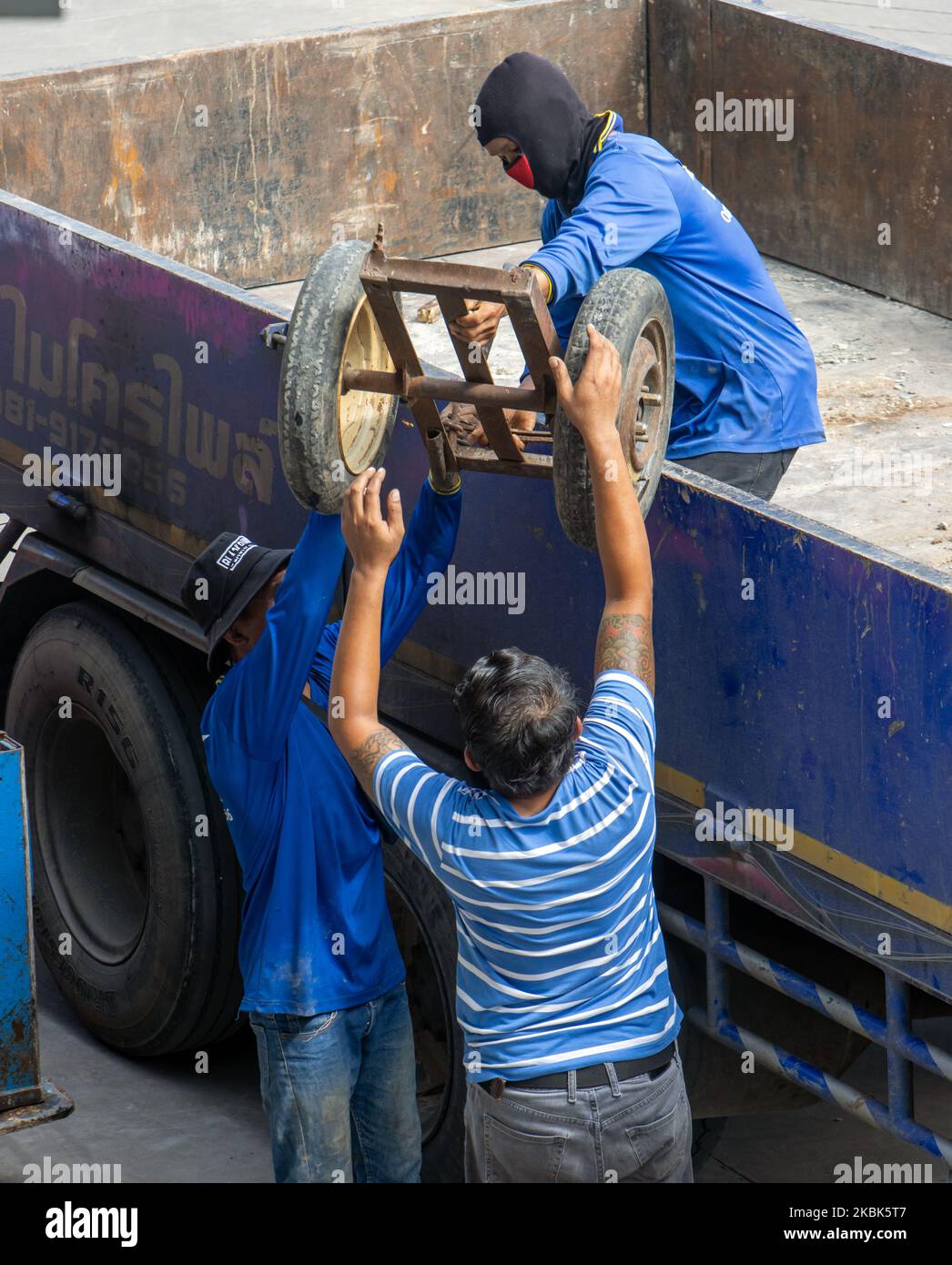 SAMUT PRAKAN, THAILAND, SEP 16 2022, Arbeiter entladen einen Wagen aus dem Ladebett eines Lastwagens Stockfoto