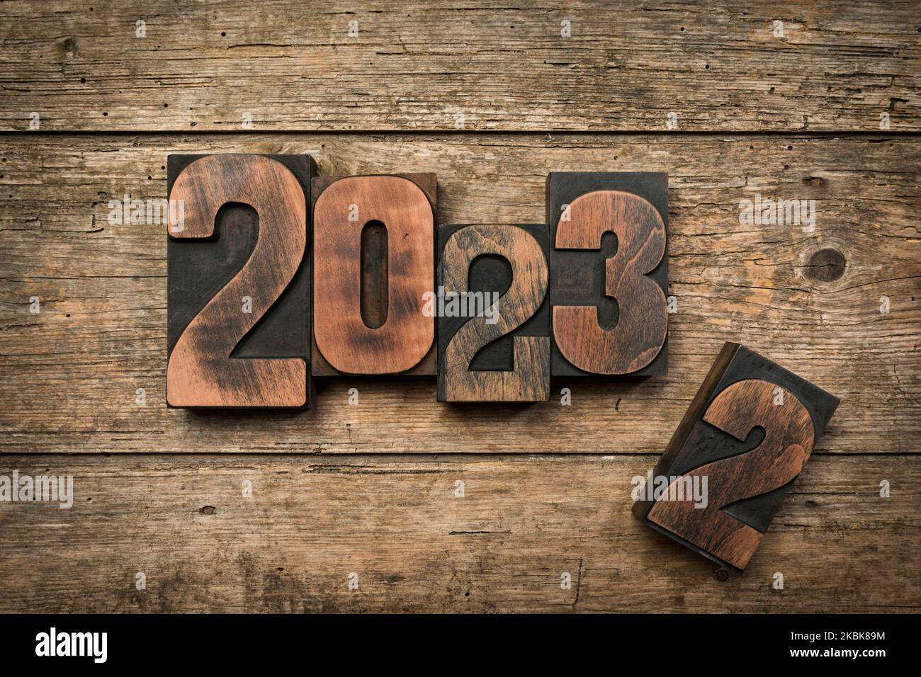 Wechsel von 2022 auf 2023 geschrieben mit Vintage-Buchdruckblöcken auf rustikalem Holzhintergrund Stockfoto