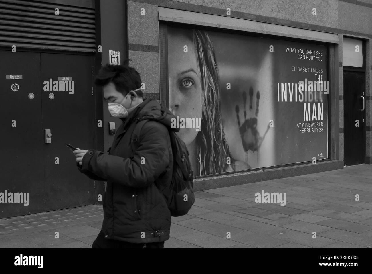 (ANMERKUNG DES HERAUSGEBERS: Dieses Bild wurde in Schwarzweiß konvertiert.) Ein Mann trägt eine Maske, als er an einem Werbefilm namens The Invisible man in einem verlassenen Leicester Square vorbeigeht, der am 20. März 2020 in London, England, zu sehen ist. Das Coronavirus (COVID-19) hat sich in mindestens 182 Ländern ausgebreitet und hat über 10.000 Menschenleben gefordert und mehr als 250.000 Menschen infiziert. Im Vereinigten Königreich gab es inzwischen 3.269 diagnostizierte Fälle und 144 Todesfälle. (Foto von Alberto Pezzali/NurPhoto) Stockfoto