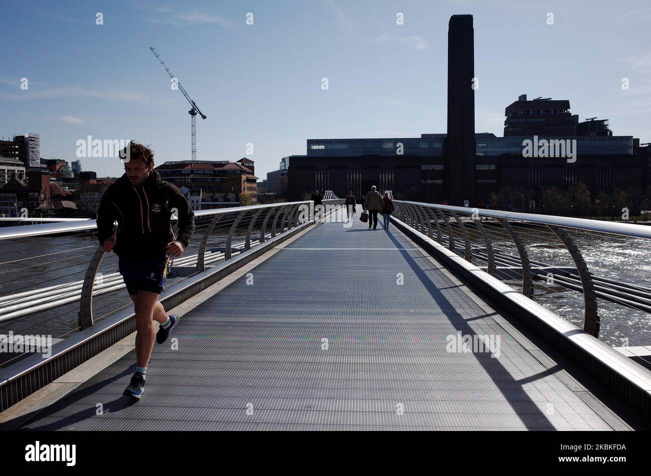 Ein Mann joggt am 24. März 2020 entlang einer fast menschenleeren Millennium Bridge, weg von der Tate Modern Art Gallery (im Hintergrund) und in Richtung St Paul's Cathedral in London, England. Der britische Premierminister Boris Johnson hat gestern Abend eine beispiellose „Sperre“ des Vereinigten Königreichs eingeleitet, um die Ausbreitung des Covid-19-Coronavirus zu bekämpfen, indem er die Bürger anwies, ihre Häuser nicht zu verlassen, außer sich aus medizinischen Gründen lebensnotwendige Dinge zu kaufen und zu versorgen, um zur Arbeit zu reisen, wenn dies „absolut notwendig“ ist, Und einmal am Tag trainieren. Alle Geschäfte, die nicht notwendige Waren verkaufen, wurden zur Schließung bestellt. Ein weiterer Stockfoto