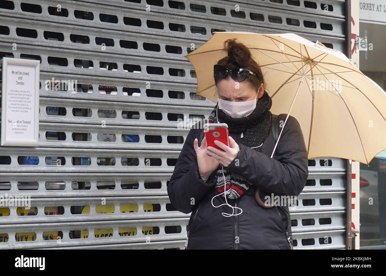 Am 25.. März 2020 wird vor einem geschlossenen Geschäft in der Nähe des Elmhurst Hospital, dem Zentrum des Coronavirus New York, eine Frau mit Gesichtsbedeckung gesehen. (Foto von Selcuk Acar/NurPhoto) Stockfoto