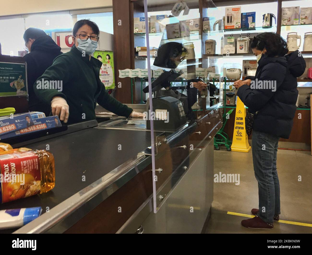 Kassiererin hinter einem neu installierten Plexiglas-Schild (Acryl), um sie am 27. März 2020 in einem Lebensmittelgeschäft in Markham, Ontario, Kanada, vor dem neuartigen Coronavirus (COVID-19) zu schützen. Lebensmittelgeschäfte und andere Einzelhändler haben begonnen, Plexiglasschilde an den Kassen zu installieren und soziale Distanzierungen (physische Distanzierungen) durchzusetzen, um die Ausbreitung von COVID-19 zu verlangsamen. (Foto von Creative Touch Imaging Ltd./NurPhoto) Stockfoto