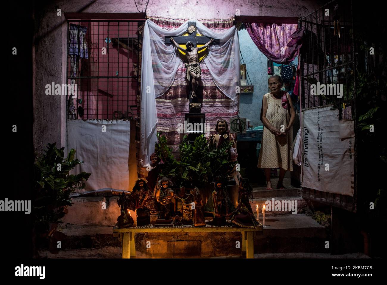 Eine Frau zeigt während des Gründonnerstags, 9. April 2020 in Navotas, Philippinen, brennende Kerzen und Statuen von religiösen Persönlichkeiten vor ihrem Haus. Die meisten religiösen Aktivitäten wurden aufgrund der erhöhten Quarantäne der Gemeinschaft (ECQ) über der Insel Luzon ausgesetzt. (Foto: Lisa Marie David/NurPhoto) Stockfoto