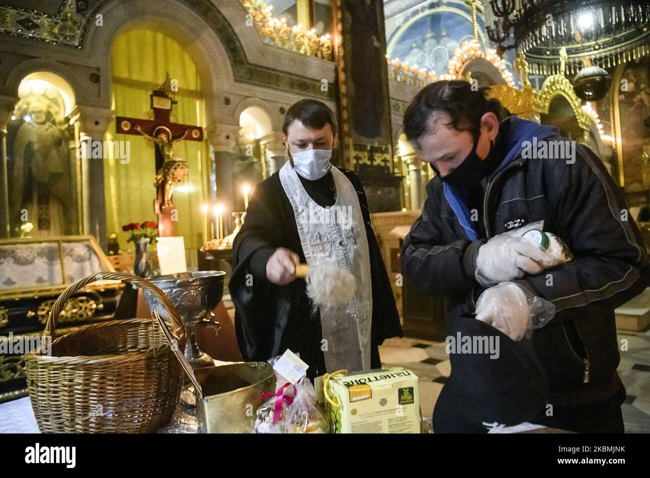 Am Vorabend des orthodoxen Osterdienstes in einer leeren Wolodymysky-Kathedrale, inmitten des Ausbruchs der Coronavirus-Krankheit COVID-19 in Kiew, Ukraine, besprengt ein orthodoxer Priester am 18. April 2020 das traditionelle ukrainische Osterbrot mit Weihwasser. (Foto von Maxym Marusenko/NurPhoto) Stockfoto