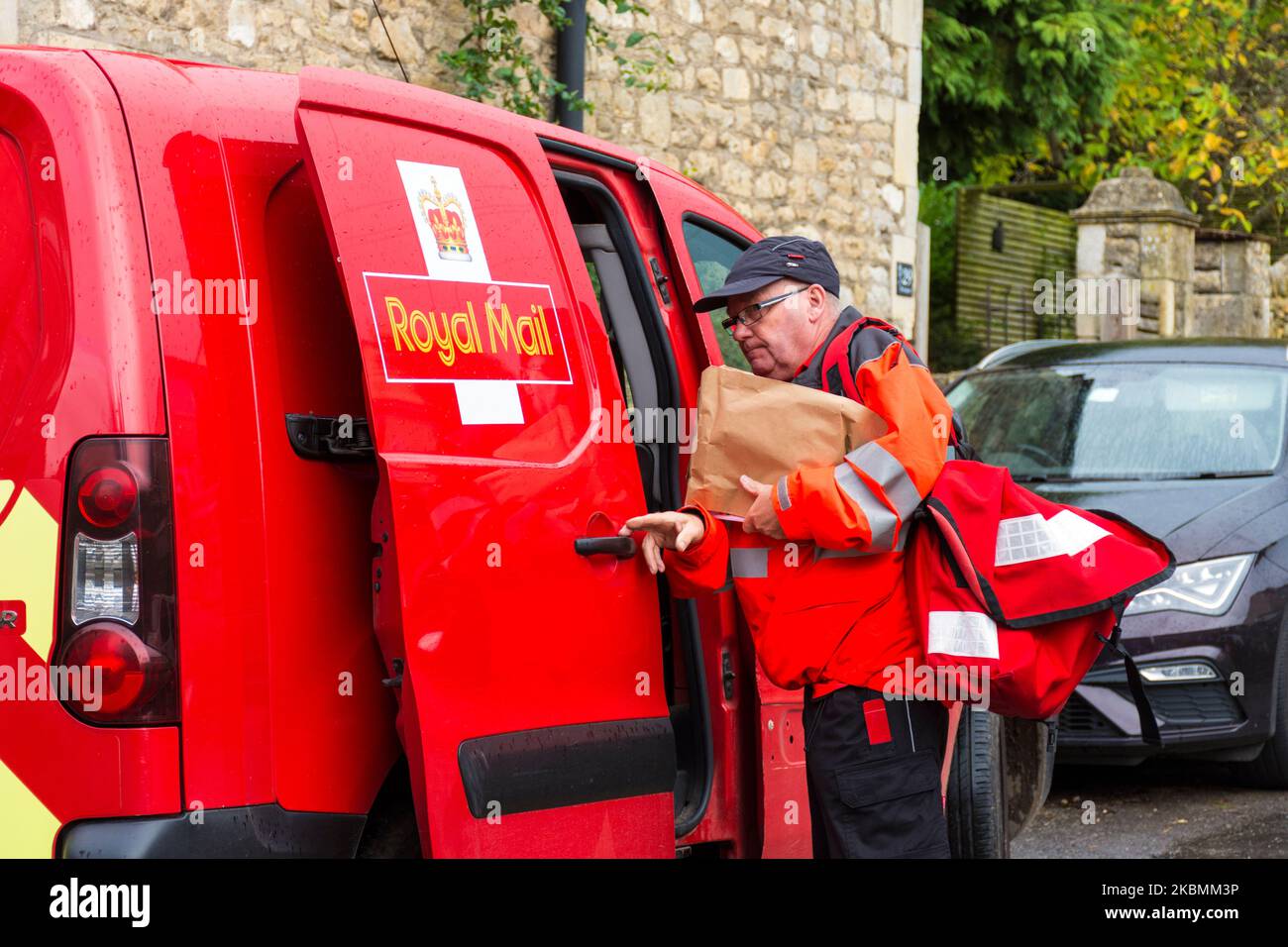 Royal Mail Postarbeiter nimmt Lieferungen auf seiner Runde in Batheaston, Somerset, England, Großbritannien, vor Stockfoto