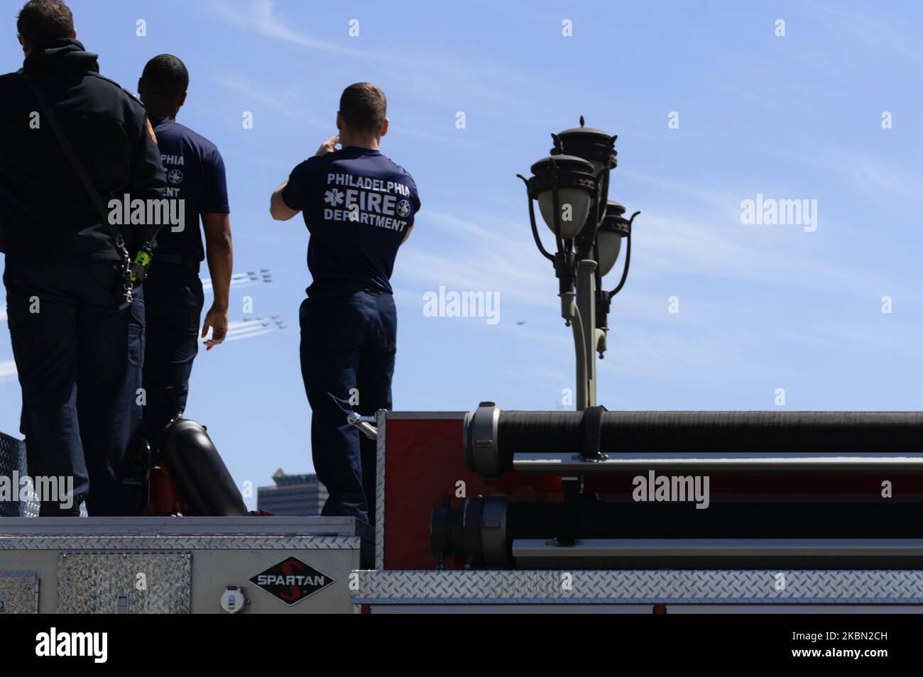 Auf der Oberseite ihrer LKW-Feuerwehrleute stehend, beobachten Sie die US Navy Blue Angles F/A-18 und die US Air Force Thunderbirds F-16 Fighting Falcon beim Überfliegen der Skyline von Center City in Philadelphia, PA, am 28. April 2020. Die Übung, die laut Berichten 60,000 USD pro Stunde kostet, ist Teil einer landesweiten Hommage an die Mitarbeiter der Gesundheitsfürsorge in der Region. (Foto von Bastiaan Slabbers/NurPhoto) Stockfoto