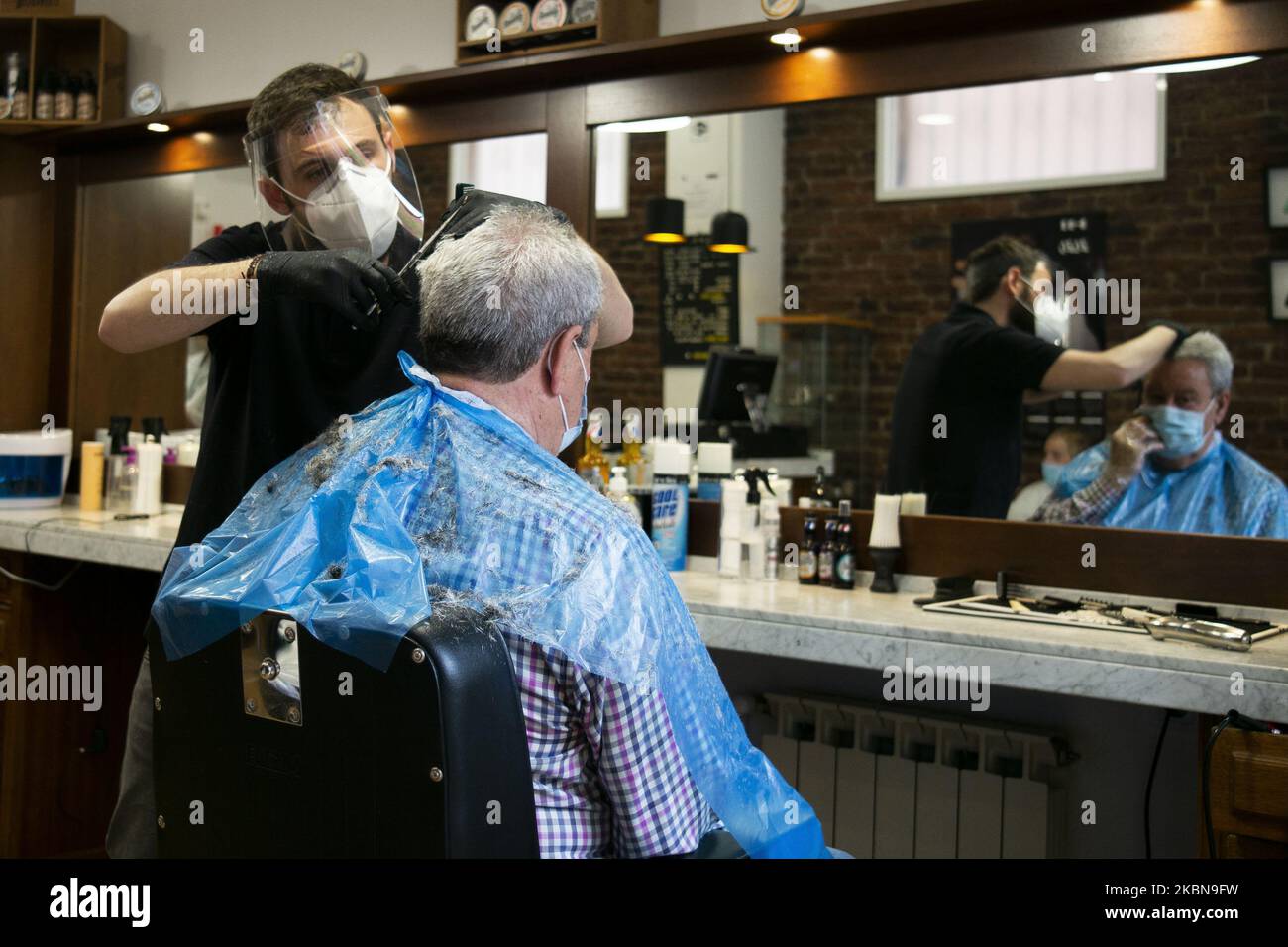 Ein Mann bekommt einen Haarschnitt bei einem Friseur, als das Land am 4. Mai 2020 in Madrid, Spanien, offiziell die erste von vier Phasen der Deeskalation einleitet. Da Spanien die akute Phase der Krankheit verblassen sieht, beginnt am Montag offiziell die erste von vier Phasen der Deeskalation. Einige Unternehmen wie Friseure, Zahnärzte oder Eisenwarengeschäfte beginnen zu operieren, aber Kunden werden nur nach Vereinbarung zugelassen. (Foto von Oscar Gonzalez/NurPhoto) Stockfoto