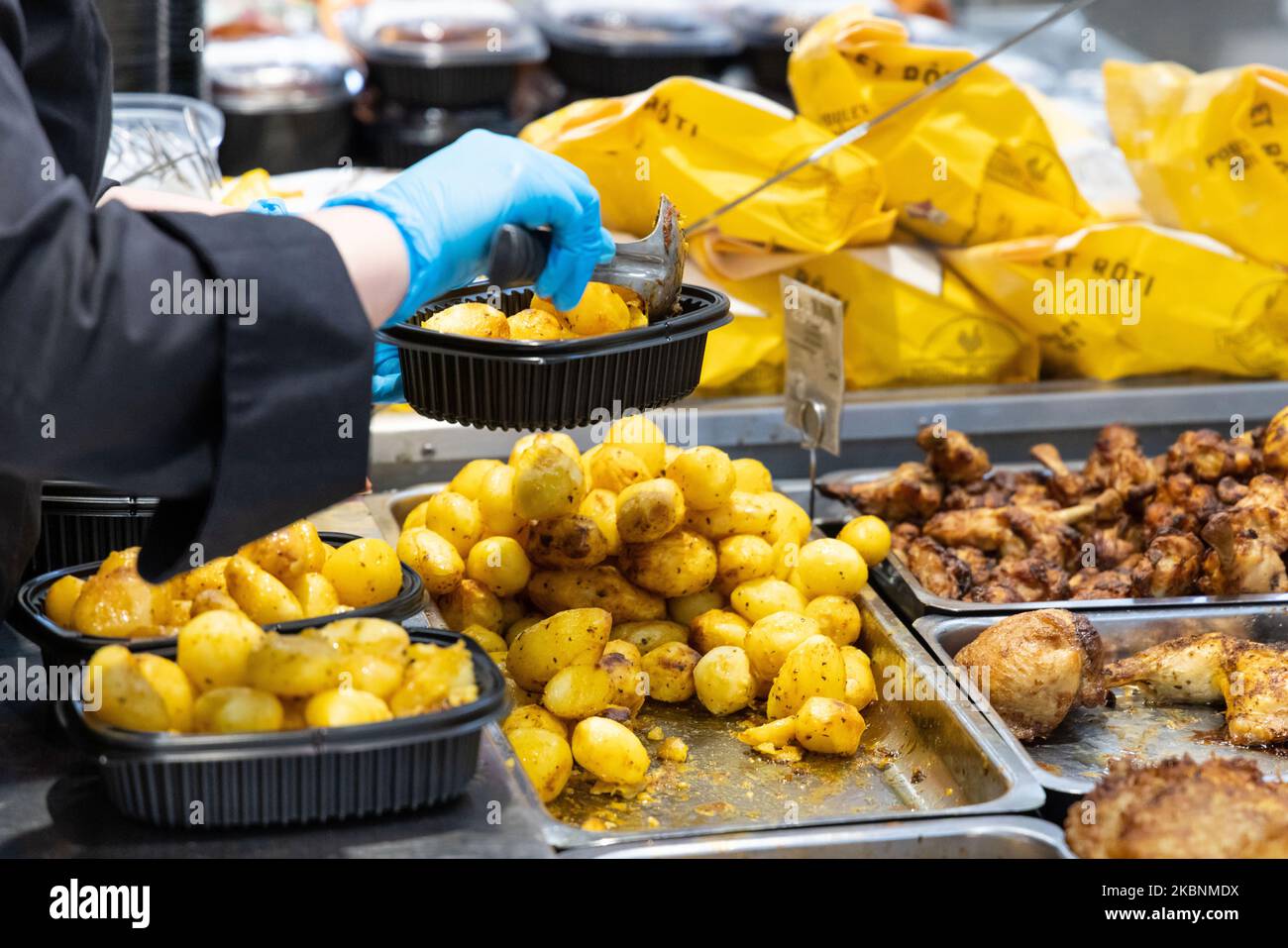 Frischer Delikatessenladen in einem Cora-Supermarkt. Mitarbeiter legt Kartoffeln in Kunststoffschalen Stockfoto