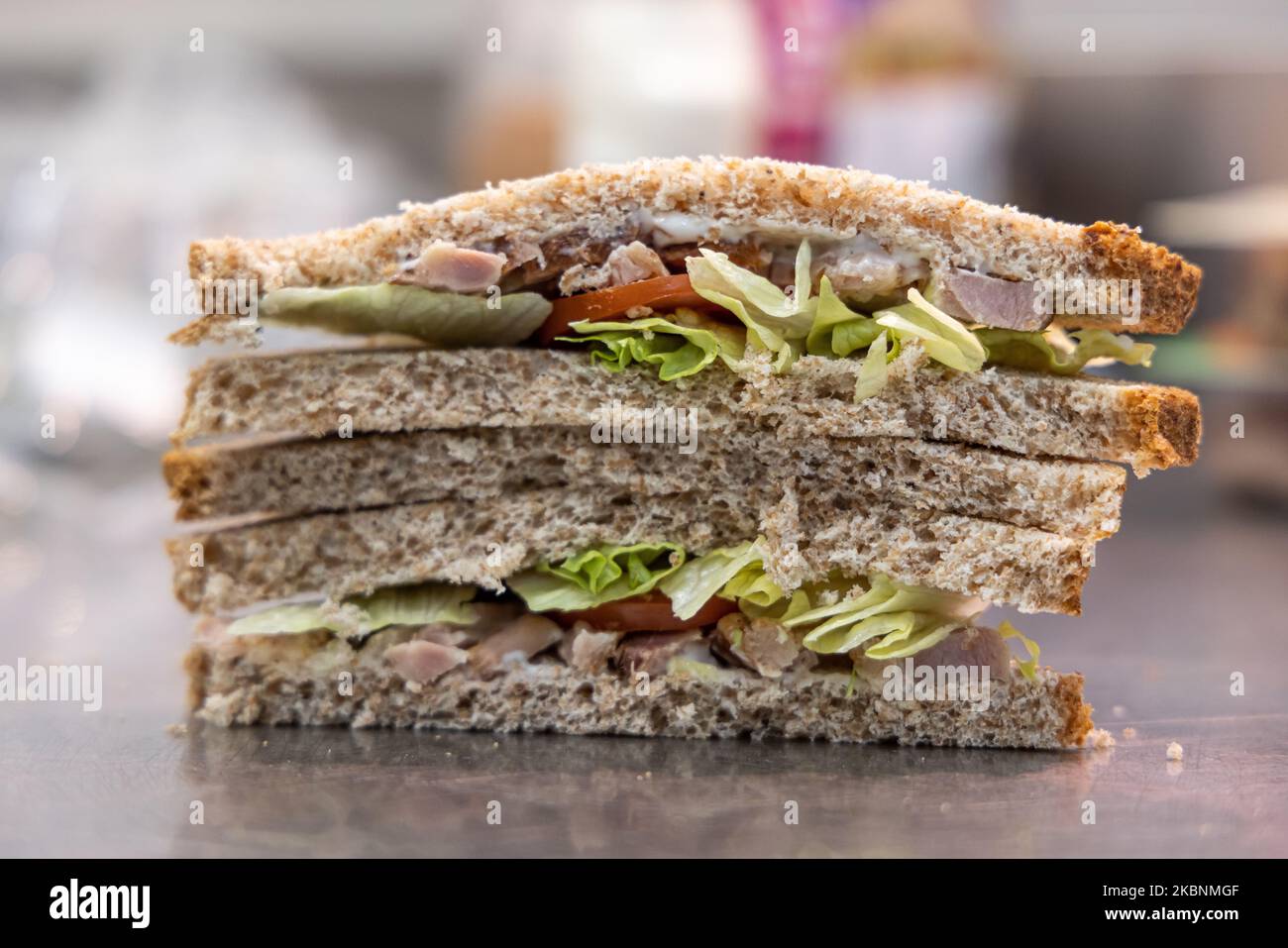 Frischer Delikatessenladen in einem Cora-Supermarkt. Mitarbeiter bereitet ein Sandwich mit Brotscheiben zu Stockfoto