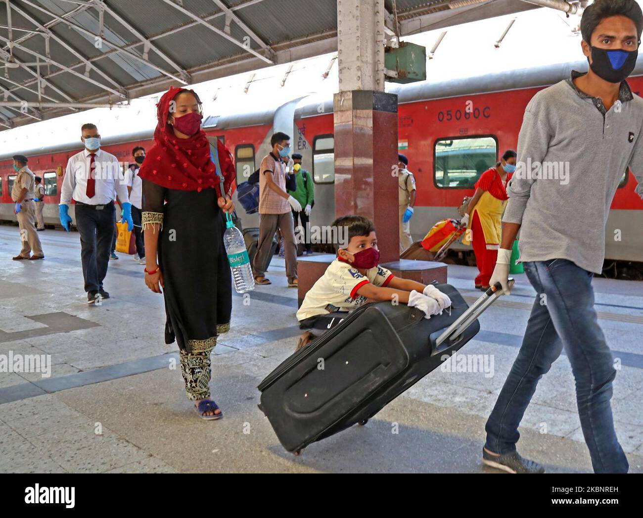 Ein Junge sitzt auf einem Trolley-Beutel, der von seinem Vater bei der Ankunft aus Neu-Delhi in einem Special AC Zug gezogen wird, kommt am 14. Mai 2020 in Kalkutta, Indien, am Bahnhof Howrah an. Das Land hat am Dienstag Teile seines riesigen Schienennetzes wiedereröffnet und betreibt eine begrenzte Anzahl von Zügen, um trotz des anhaltenden Anstiegs der Coronavirus-Infektionen eine fast siebenwöchige Sperre zu lockern. (Foto von Debajyoti Chakraborty/NurPhoto) Stockfoto