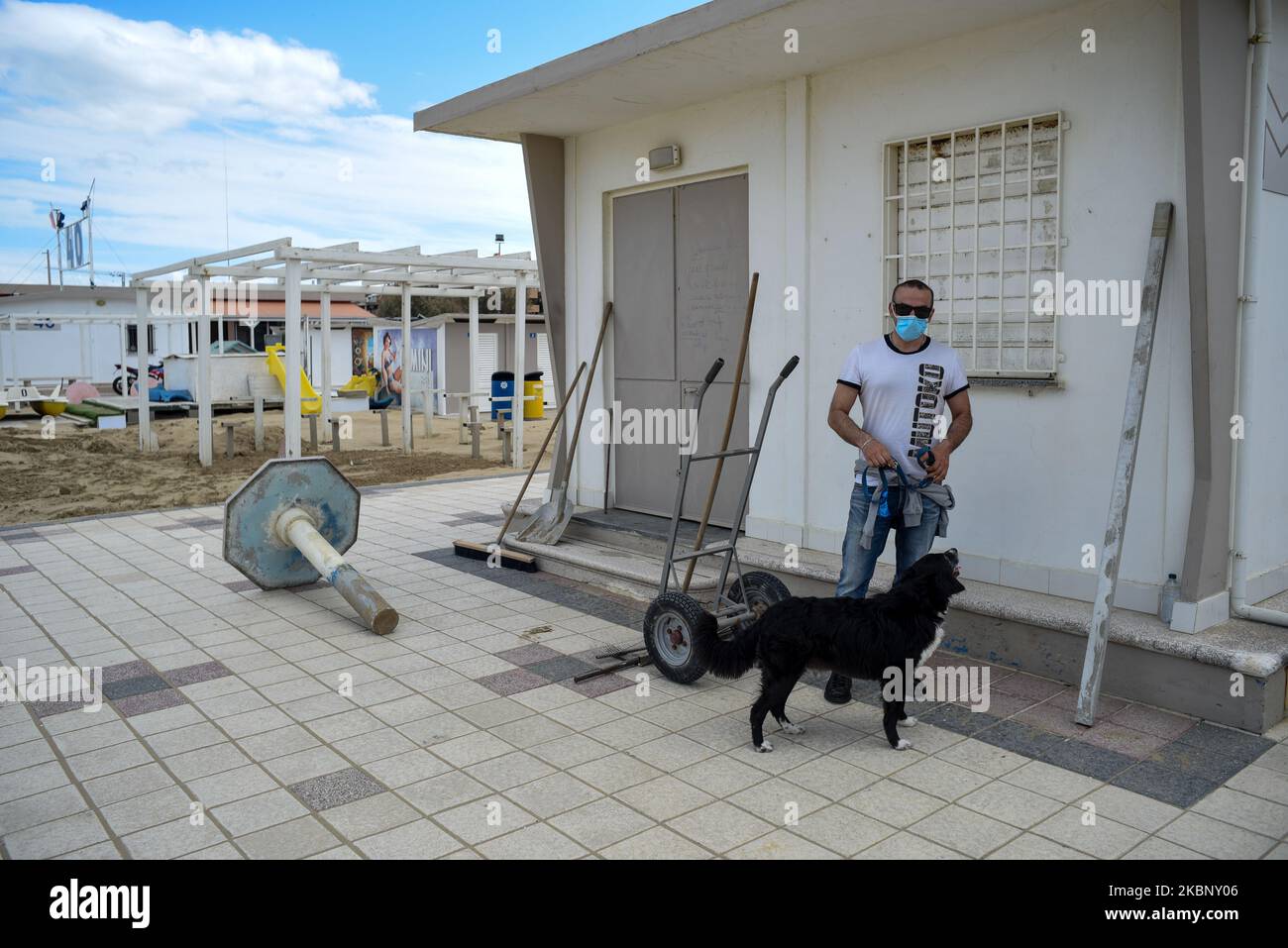 Ein Mann mit einer Gesichtsmaske geht mit seinem Hund zwischen den Badeanstalten der Riviera Romagnola, die nach dem Coronavirus-Notfall noch geschlossen sind. Rimini, Italien, 15. Mai 2020. (Foto von Andrea Savorani Neri/NurPhoto) Stockfoto