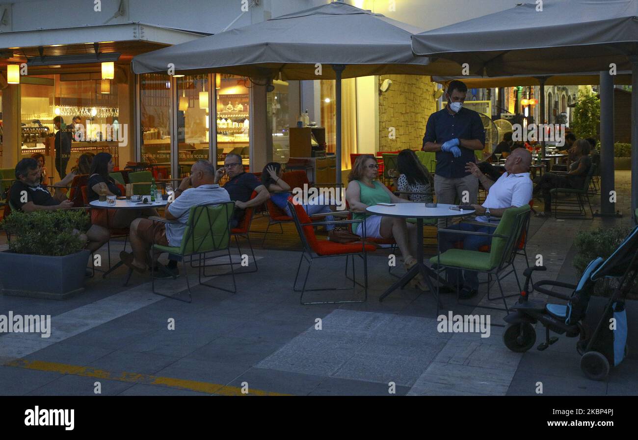 Ein Kellner in einer Schutzmaske und Handschuhen, der sich mit Besuchern auf dem Terrassencafe in Limassol unterhielt. Zypern, Donnerstag, 21. Mai 2020 Zypern hat am Donnerstag einen großen Schritt zur Rückkehr zur Normalität getan, als die meisten Einschränkungen einer zweimonatigen Aufenthaltsordnung aufgehoben wurden, die es Grundschulkindern ermöglichte, in Klassen zurückzukehren und Friseursalons und Cafeterien im Freien wieder zu öffnen. (Foto von Danil Shamkin/NurPhoto) Stockfoto