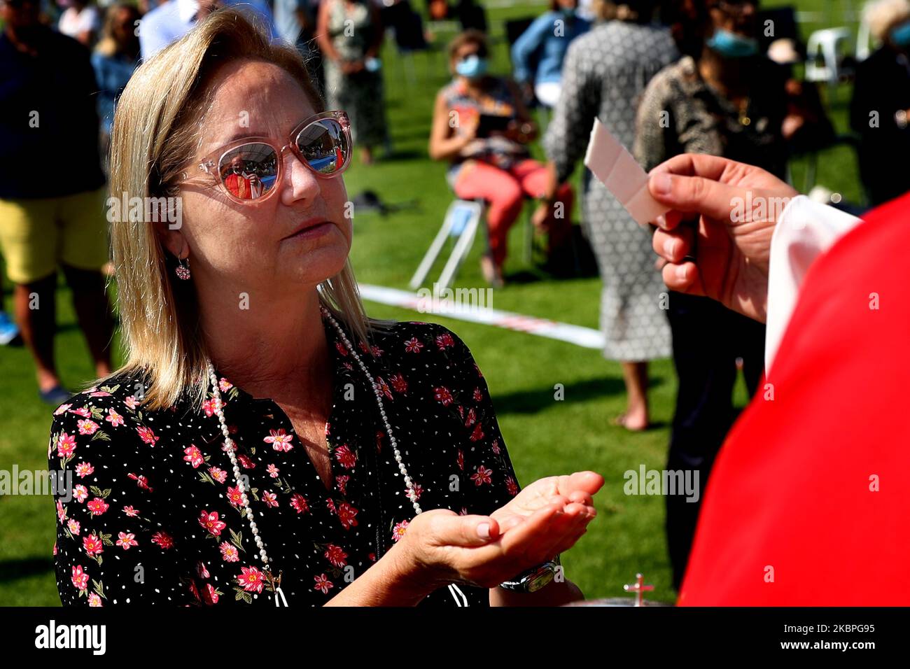 Die Reflexion des Priesters Nuno Coelho wird in der Sonnenbrille eines Gläubigen gesehen, als sie den Gastgeber während einer Freiluftmesse im Hippodrom in Cascais, Portugal, am 31. Mai 2020 inmitten der COVID-19-Pandemie empfängt. Neue Regeln für die Gläubigen und Anpassungen der Kulte wurden von der katholischen Kirche angenommen, um die Kirchen wieder zu öffnen. (Foto von Pedro FiÃºza/NurPhoto) Stockfoto