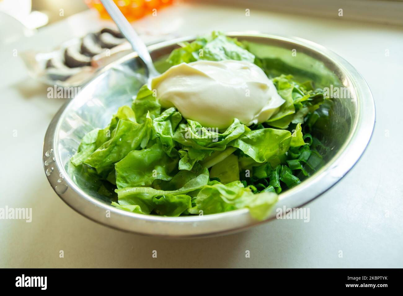 Saure Creme auf grünem Salat in einer silbernen Schüssel Stockfoto
