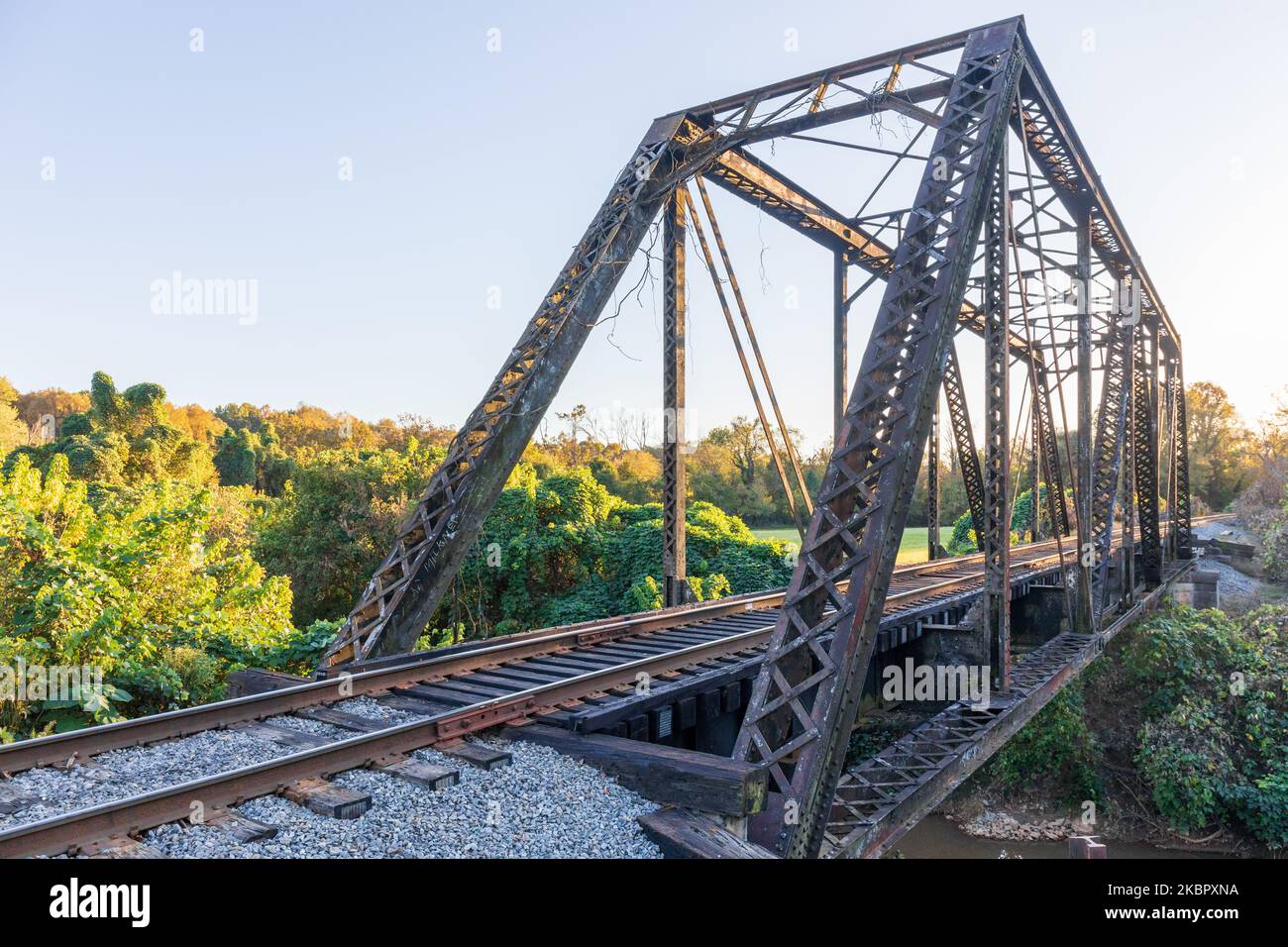 ELKIN, NORTH CAROLINA, USA-14. OKTOBER 2022: Stahlträger-Eisenbahnbrücke in der Innenstadt. Am späten Nachmittag im Frühherbst. Stockfoto