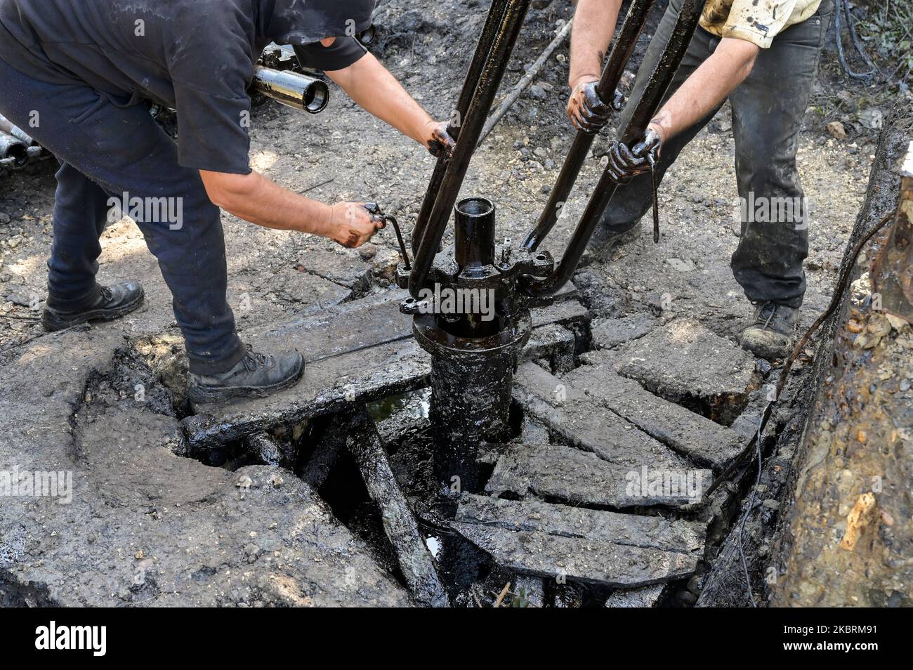 ALBANIEN, Kuçova, benannt Stalin Stadt von 1950 to1991, Rohölfeld und Bohrpumpe aus kommunistischer Zeit, noch in Betrieb und umweltschädlich, Arbeiter mit Bohrrohr / ALBANIEN, Kucova, von 1950 bis 1991 Qyteti Stalin, Stalinstadt, Erdölförderung, alte Oelföerderpumpe, die heute noch zur Ölförderung in Betrieb sind, Work with Bohrgestänge Stockfoto