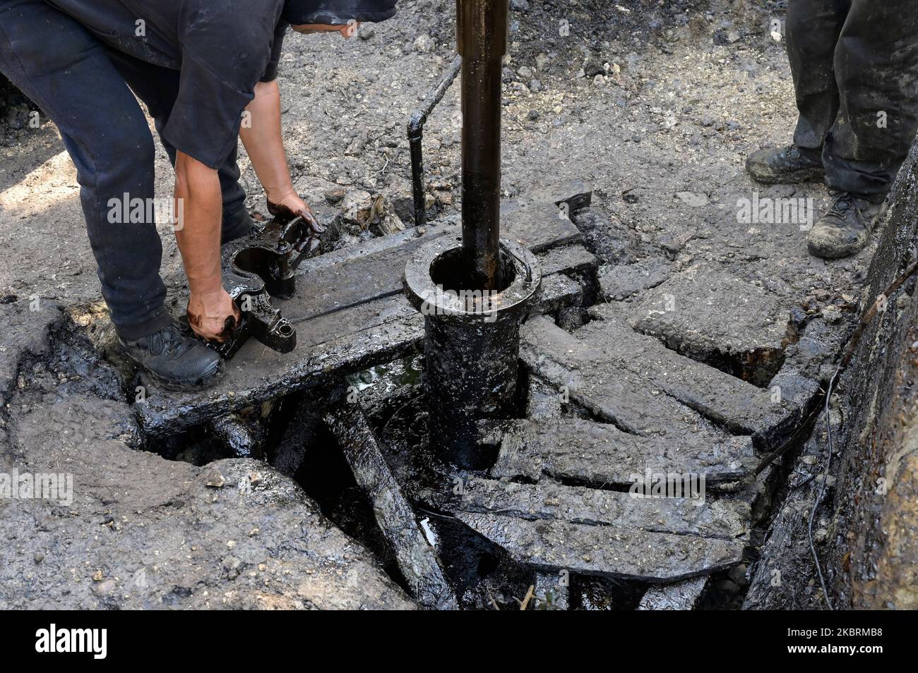 ALBANIEN, Kuçova, benannt Stalin Stadt von 1950 to1991, Rohölfeld und Bohrpumpe aus kommunistischer Zeit, noch in Betrieb und umweltschädlich, Arbeiter mit Bohrrohr / ALBANIEN, Kucova, von 1950 bis 1991 Qyteti Stalin, Stalinstadt, Erdölförderung, alte Oelföerderpumpe, die heute noch zur Ölförderung in Betrieb sind, Work with Bohrgestänge Stockfoto