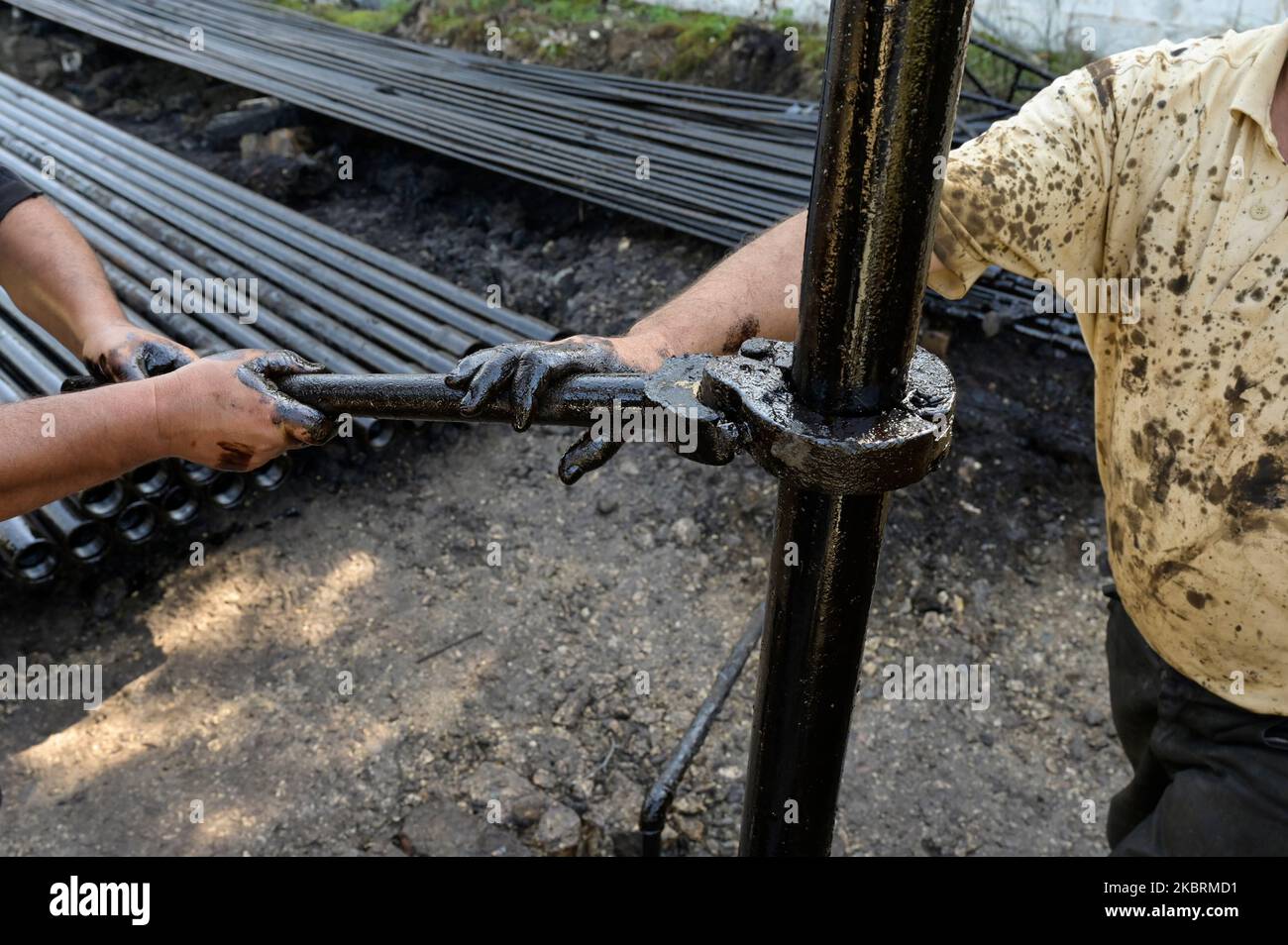 ALBANIEN, Kuçova, benannt Stalin Stadt von 1950 to1991, Rohölfeld und Bohrpumpe aus kommunistischer Zeit, noch in Betrieb und umweltschädlich, Arbeiter mit Bohrrohr / ALBANIEN, Kucova, von 1950 bis 1991 Qyteti Stalin, Stalinstadt, Erdölförderung, alte Oelföerderpumpe, die heute noch zur Ölförderung in Betrieb sind, Work with Bohrgestänge Stockfoto