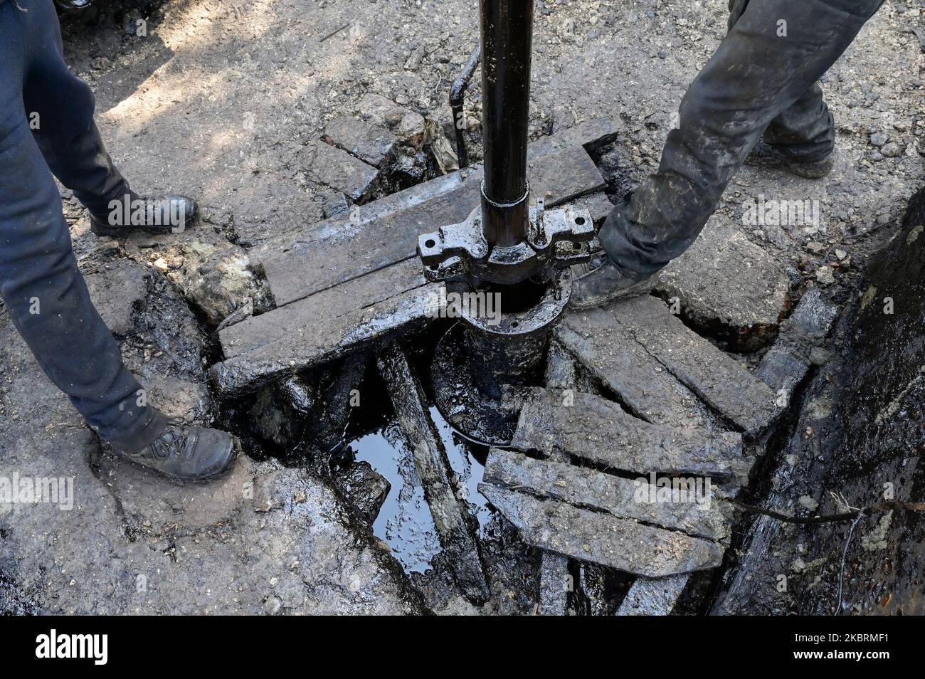 ALBANIEN, Kuçova, benannt Stalin Stadt von 1950 to1991, Rohölfeld und Bohrpumpe aus kommunistischer Zeit, noch in Betrieb und umweltschädlich, Arbeiter mit Bohrrohr / ALBANIEN, Kucova, von 1950 bis 1991 Qyteti Stalin, Stalinstadt, Erdölförderung, alte Oelföerderpumpe, die heute noch zur Ölförderung in Betrieb sind, Work with Bohrgestänge Stockfoto