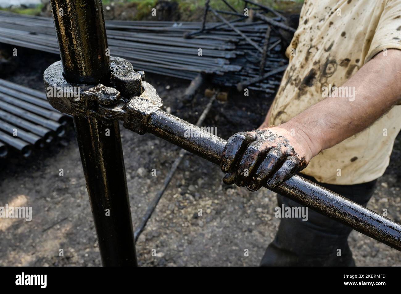 ALBANIEN, Kuçova, benannt Stalin Stadt von 1950 to1991, Rohölfeld und Bohrpumpe aus kommunistischer Zeit, noch in Betrieb und umweltschädlich, Arbeiter mit Bohrrohr / ALBANIEN, Kucova, von 1950 bis 1991 Qyteti Stalin, Stalinstadt, Erdölförderung, alte Oelföerderpumpe, die heute noch zur Ölförderung in Betrieb sind, Work with Bohrgestänge Stockfoto