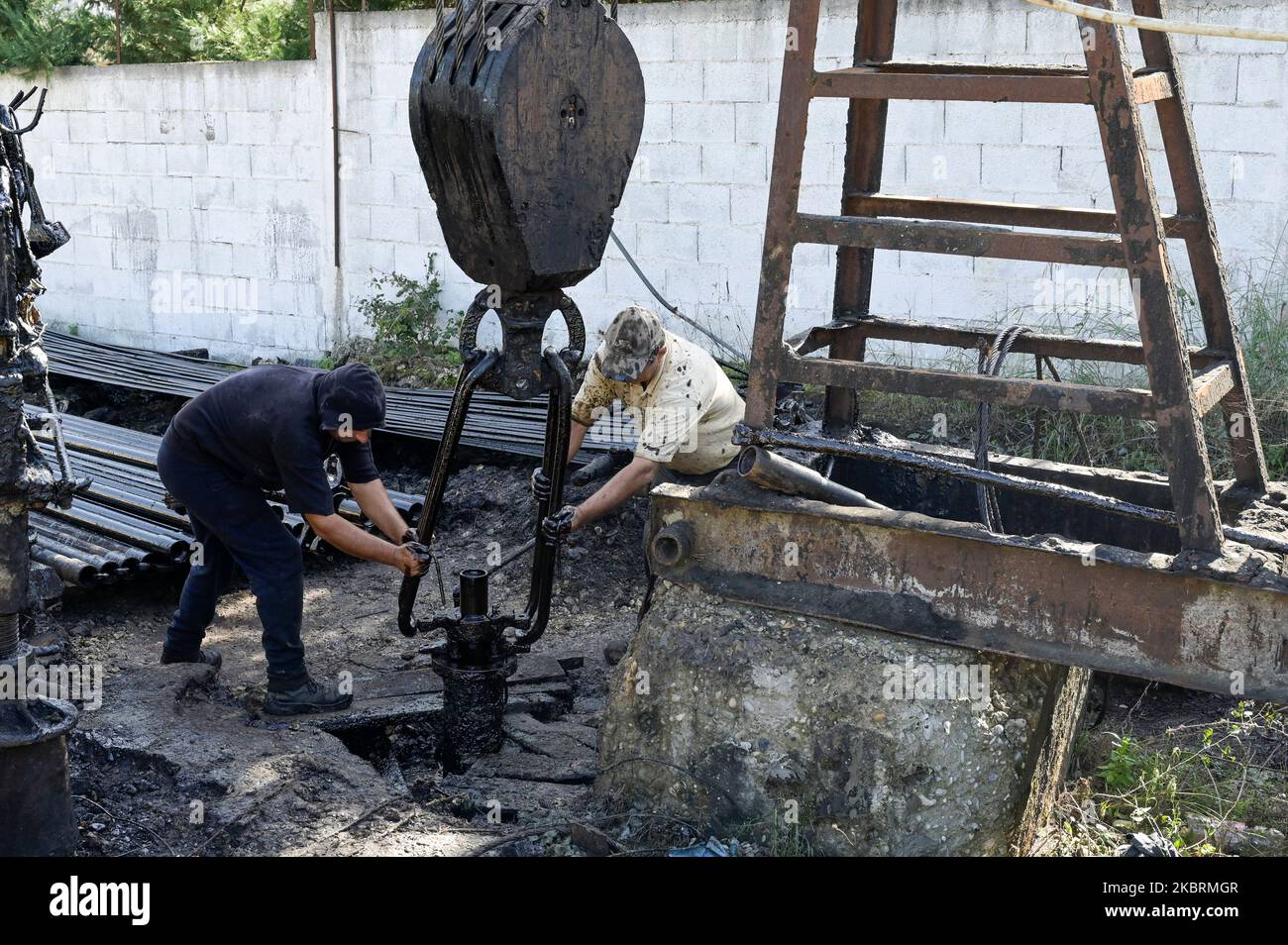 ALBANIEN, Kuçova, benannt Stalin Stadt von 1950 to1991, Rohölfeld und Bohrpumpe aus kommunistischer Zeit, noch in Betrieb und umweltschädlich, Arbeiter mit Bohrrohr / ALBANIEN, Kucova, von 1950 bis 1991 Qyteti Stalin, Stalinstadt, Erdölförderung, alte Oelföerderpumpe, die heute noch zur Ölförderung in Betrieb sind, Work with Bohrgestänge Stockfoto