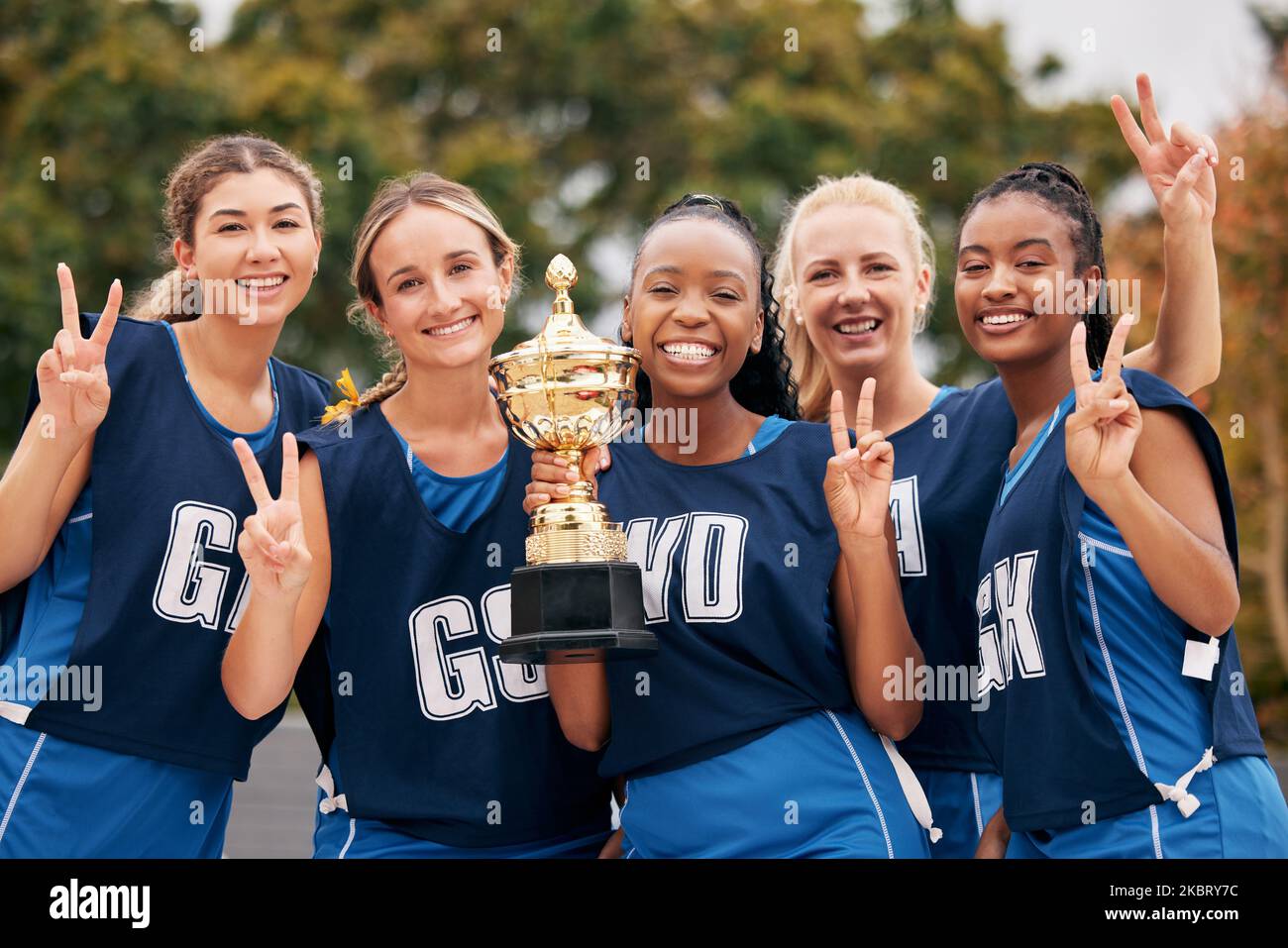 Sport, Netball und Trophäe mit einem Frauenteam zur Feier eines Sieges oder einer Errungenschaft als Siegergruppe. Frieden, Sieg und Teamarbeit mit einer Frau Stockfoto