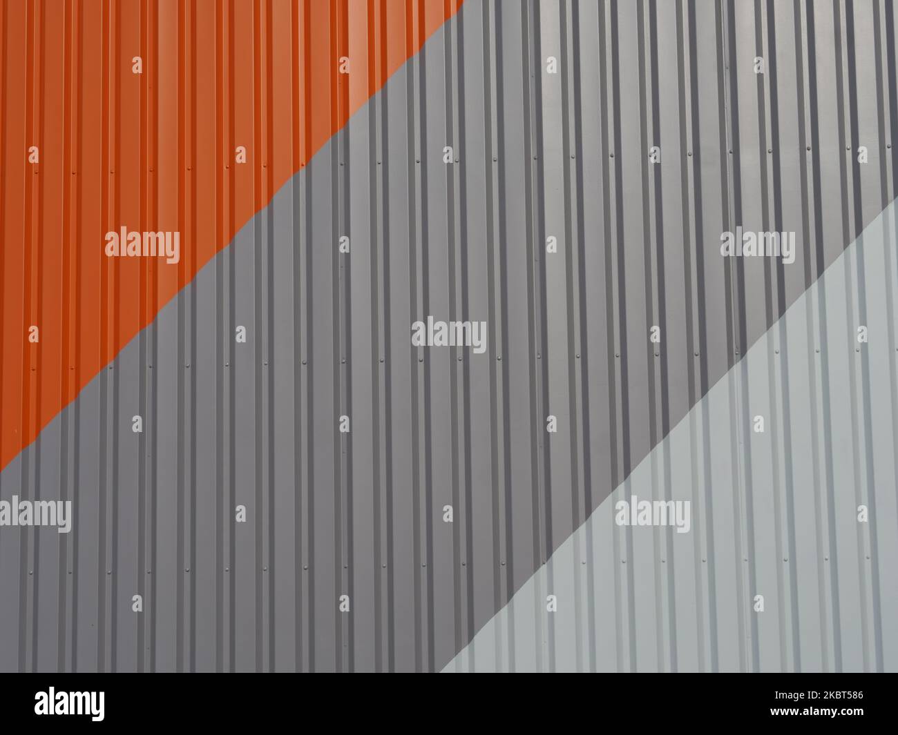Außenwand aus Metall in den Farben orange, dunkelgrau, hellgrau. Die Farben sind diagonal angeordnet. Abstrakter Hintergrund Stockfoto