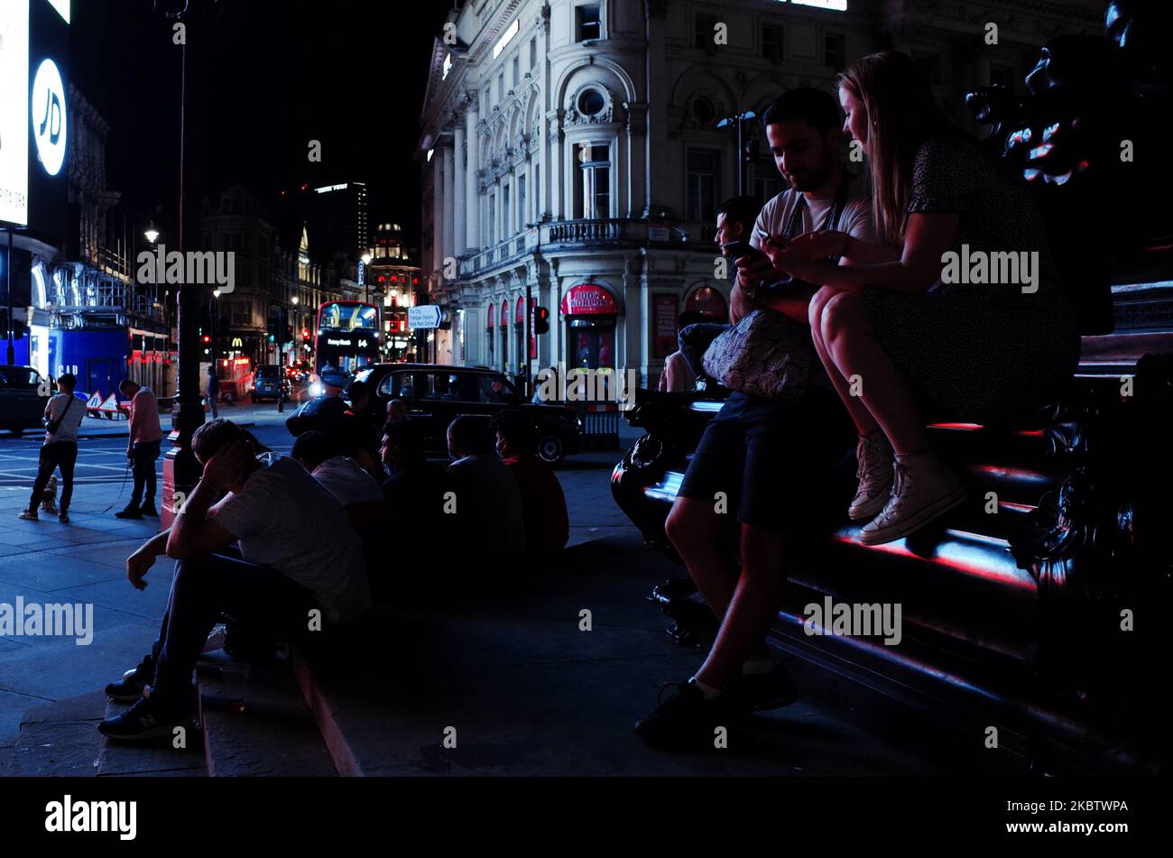 Am 18. Juli 2020 sitzen Menschen am Fuße des Shaftesbury Memorial Fountain im Piccadilly Circus spät in der Nacht in London, England. Der Aufstieg Londons aus der Blockierung des Coronavirus war bisher zögerlich, da viele Unternehmen noch nicht geöffnet waren und einige ganze Sektoren der Wirtschaft noch nicht neu gestartet wurden. Im Zentrum von London sind viele Pubs und Restaurants derzeit nur für kürzere Öffnungszeiten geöffnet, und in vielen Gegenden bleibt die Besucherzahl auffallend niedrig. (Foto von David Cliff/NurPhoto) Stockfoto