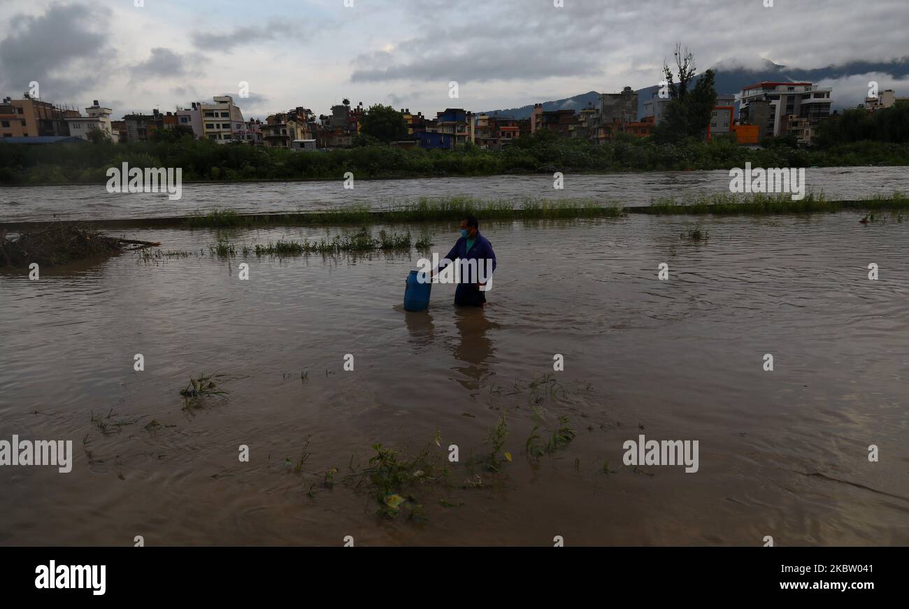 Menschen, die seine Sachen trugen, waten durch eine überflutete Straße, nachdem der Fluss aufgrund von unaufhörlichen Regenfällen in einem Slum am Ufer des Bagmati-Flusses Kathmandu, Nepal, überschwemmt wurde, 20. Juli 2020. (Foto von Saroj Baizu/NurPhoto) Stockfoto