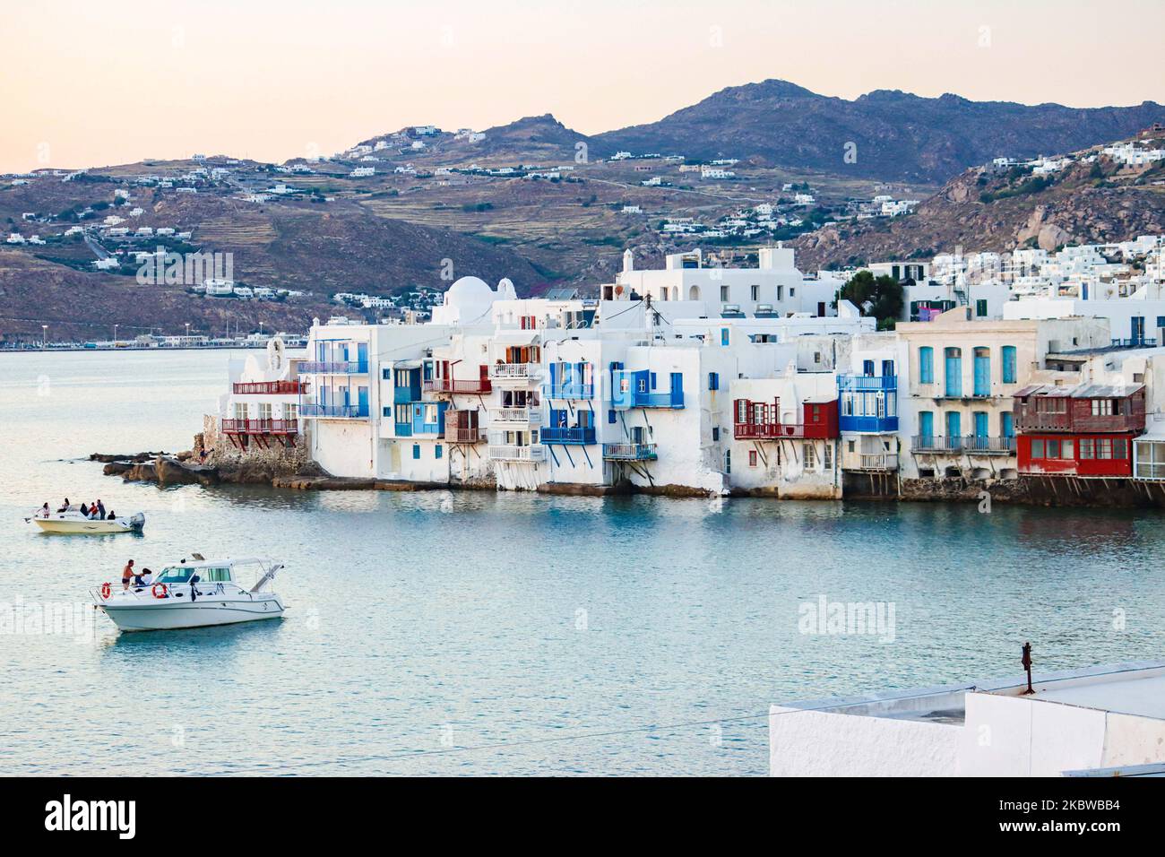 Magische Stunde bei Sonnenuntergang und Abenddämmerung in Little Venice auf Mykonos, einem der romantischsten Orte der Mittelmeerinsel am 14. Juli 2020. Dieses Viertel ist voll von eleganten und wunderschönen alten Häusern, die sich prekär am Rande der Ägäis befinden, farbenfrohe zweistöckige Gebäude im venezianischen Stil mit Holzbalkons. Diese Gebäude beherbergen heute trendige Bars, Restaurants, Galerien und mehr, aber ihr Äußeres ist immer noch einer der beliebtesten Sonnenuntergangsorte, das klassische romantische Mykonos-Erlebnis. Die berühmte Insel in den Kykladen wird als die Insel der Wi benannt Stockfoto