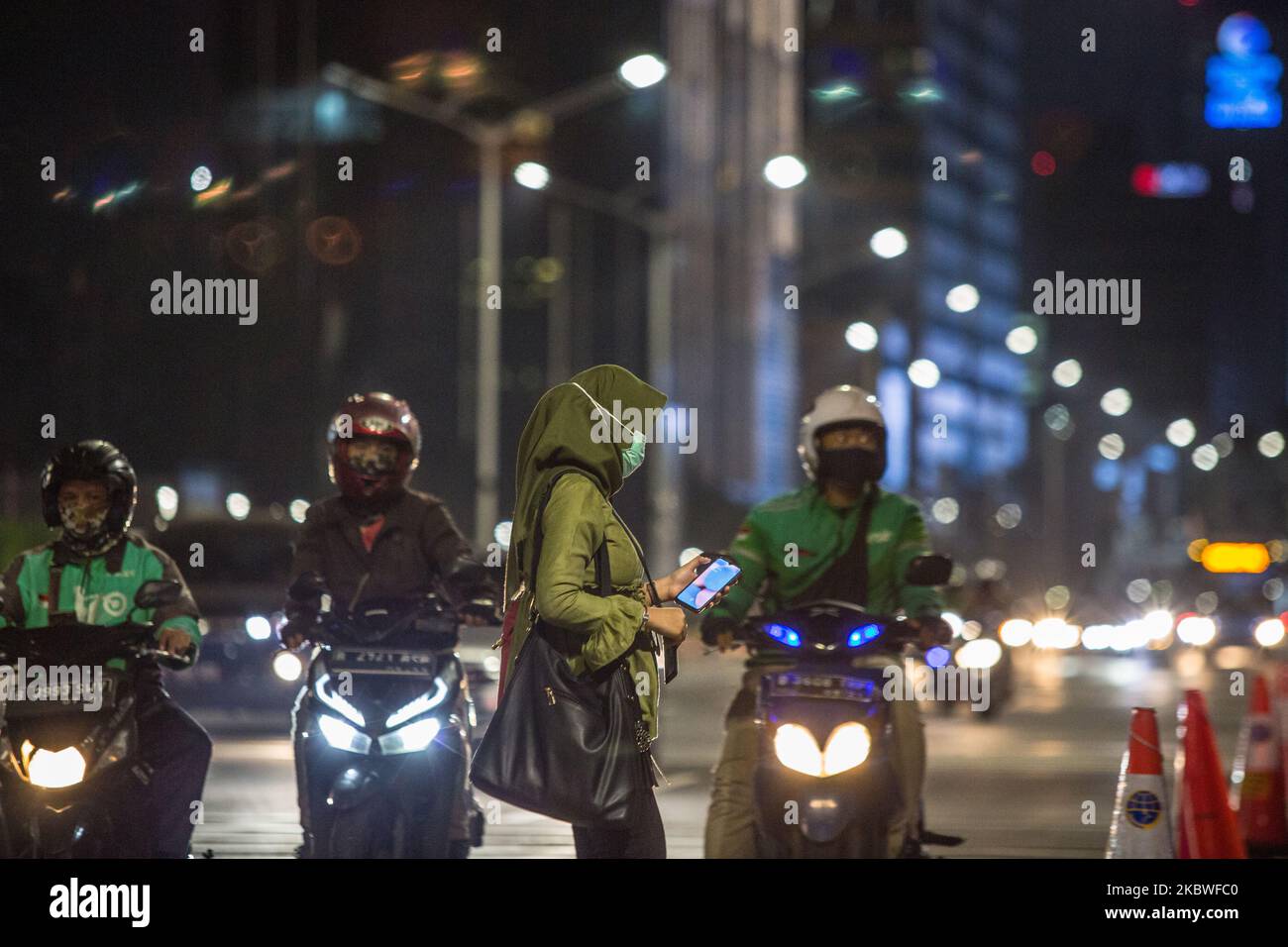 Eine Frau trägt eine schützende Gesichtsmaske, als sie am Donnerstag, dem 30. Juli 2020, die Straße in Jakarta überquert. Jakarta hat seine Übergangszeit von den großen sozialen Beschränkungen (PSBB) um weitere zwei Wochen verlängert, beginnend am Freitag, nachdem es versäumt hatte, den täglichen Anstieg der COVID-19-Fälle zu verlangsamen. Die Eigenkapitalquote oder der Prozentsatz der positiven Ergebnisse aller Tests lag in der vergangenen Woche bei 6,5 Prozent und damit über dem von der Weltgesundheitsorganisation (WHO) für Lockerungen empfohlenen Wert von 5 Prozent oder weniger. (Foto von Afriadi Hikmal/NurPhoto) Stockfoto