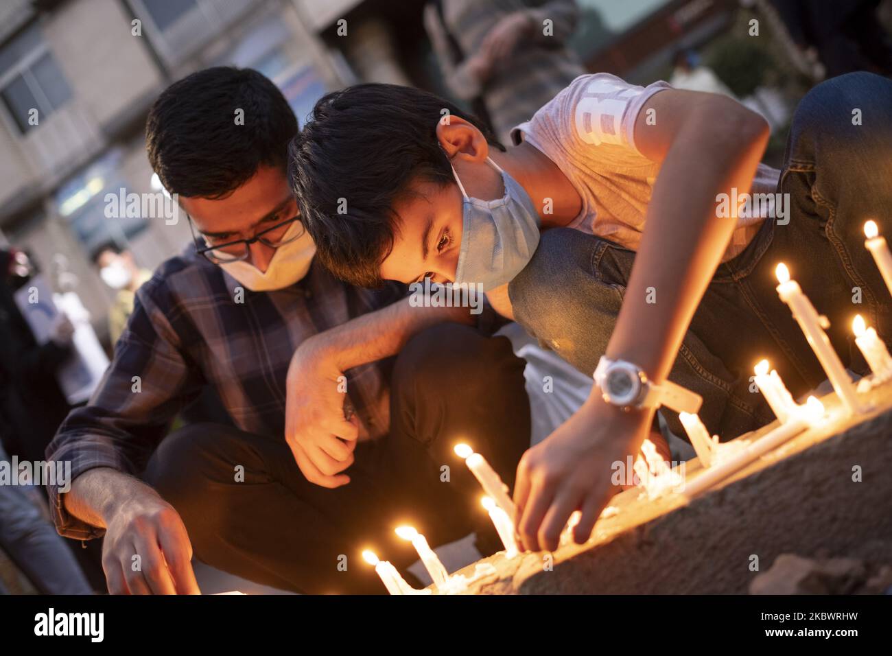 Ein iranischer Junge, der eine Schutzmaske trägt, zündet am Straßenrand vor der Botschaft des Libanon im Zentrum von Teheran eine Kerze an, als Symbol für die Sympathie des iranischen Volkes für die Opfer der jüngsten Explosionen in Beirut am 5. August 2020. (Foto von Morteza Nikoubazl/NurPhoto) Stockfoto