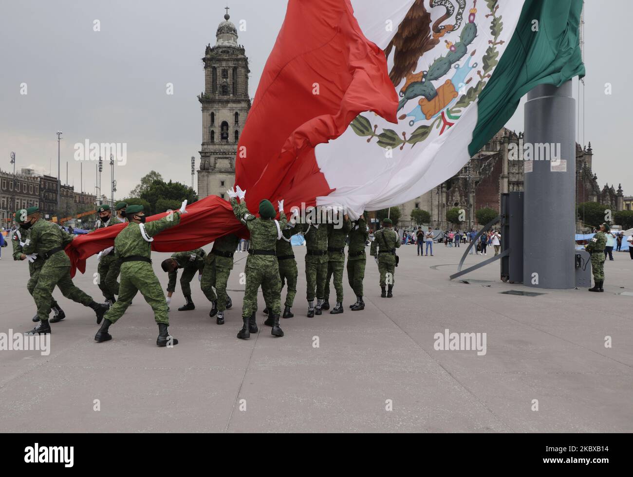 Militärmitglieder des Verteidigungsministeriums hatten während des Protokolls über den Abstieg der Nationalflagge des Fahnenmastes in der Zócalo von Mexiko-Stadt, Mexiko, am 19. August 2020 einige Schwierigkeiten, sie zu senken, nachdem sie starke Windböen in der Region registriert hatten, was die Handhabung erschwerte. (Foto von Gerardo Vieyra/NurPhoto) Stockfoto