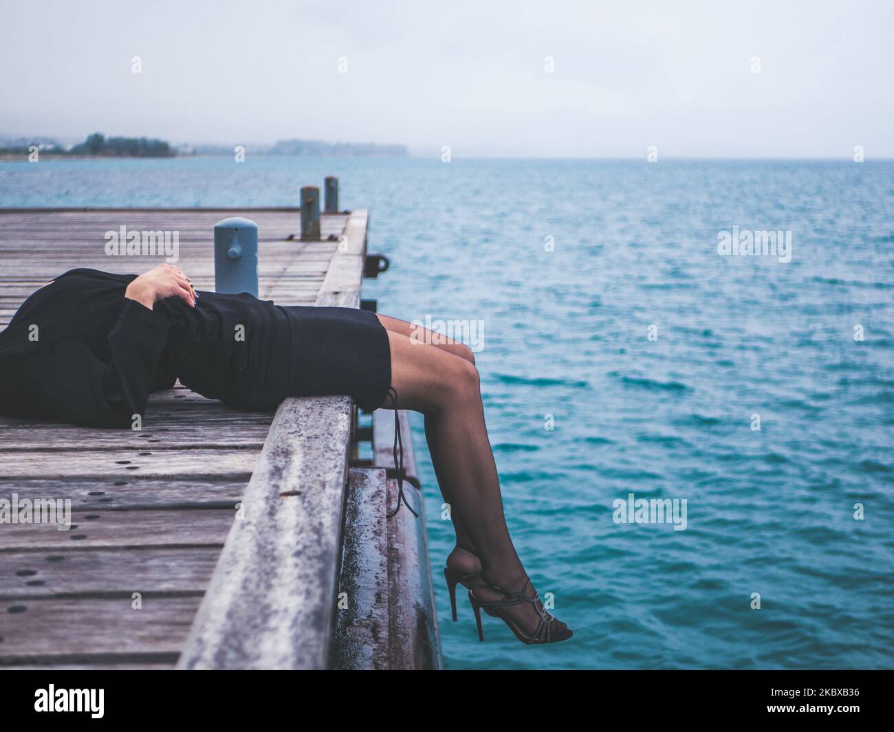 Eine Frau in Fersen, die mit den Füßen auf dem Dock lag und sich erholte Stockfoto