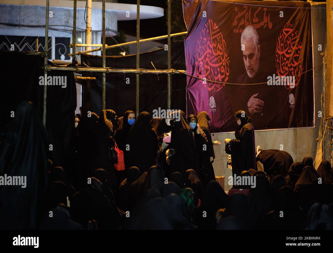 Iranische verschleierte Frauen mit Schutzmaske stehen unter einem Porträt des ehemaligen Kommandanten der Qods Force der Islamischen Revolutionsgarden (IRGC), Qasen Soleimani, während er am 28. August 2020 an einer Muharram-Trauerfeier im Süden Teherans teilnahm. Das neue Coronavirus (COVID-19) brachte das Land in die rote Situation, und die Gesundheitsbeamten warnten die Menschen, dass sie bei den Trauerzeremonien in Muharram soziale Distanzierungen und Gesundheitsprotokolle beobachtet und bereit sind für die dritte Welle der COVID-19-Krankheit, die im Herbst beginnen wird. MORTEZA NIKOUBAZL/NurPhoto (Foto von Morteza Nikoubazl Stockfoto
