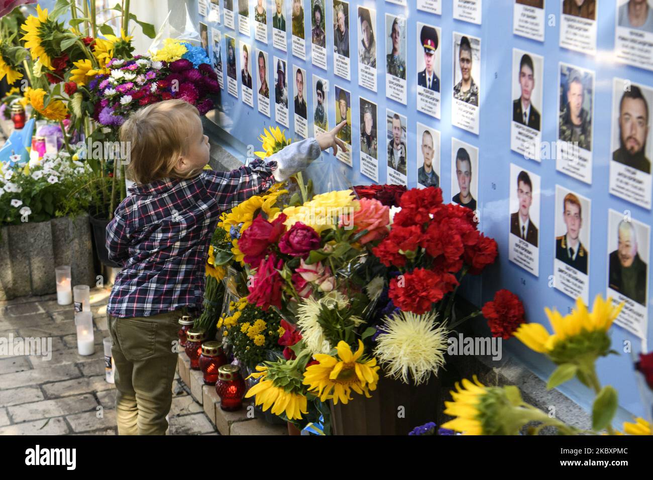Ein kleines Mädchen berührt ein Porträt über die Gedenkmauer der gefallenen Verteidiger der Ukraine im Krieg in der Ostukraine 2014-2020 während einer Gedenkfeier zum Gedenktag der gefallenen Verteidiger der Ukraine in Kiew, Ukraine, 29. August 2020. (Foto von Maxym Marusenko/NurPhoto) Stockfoto
