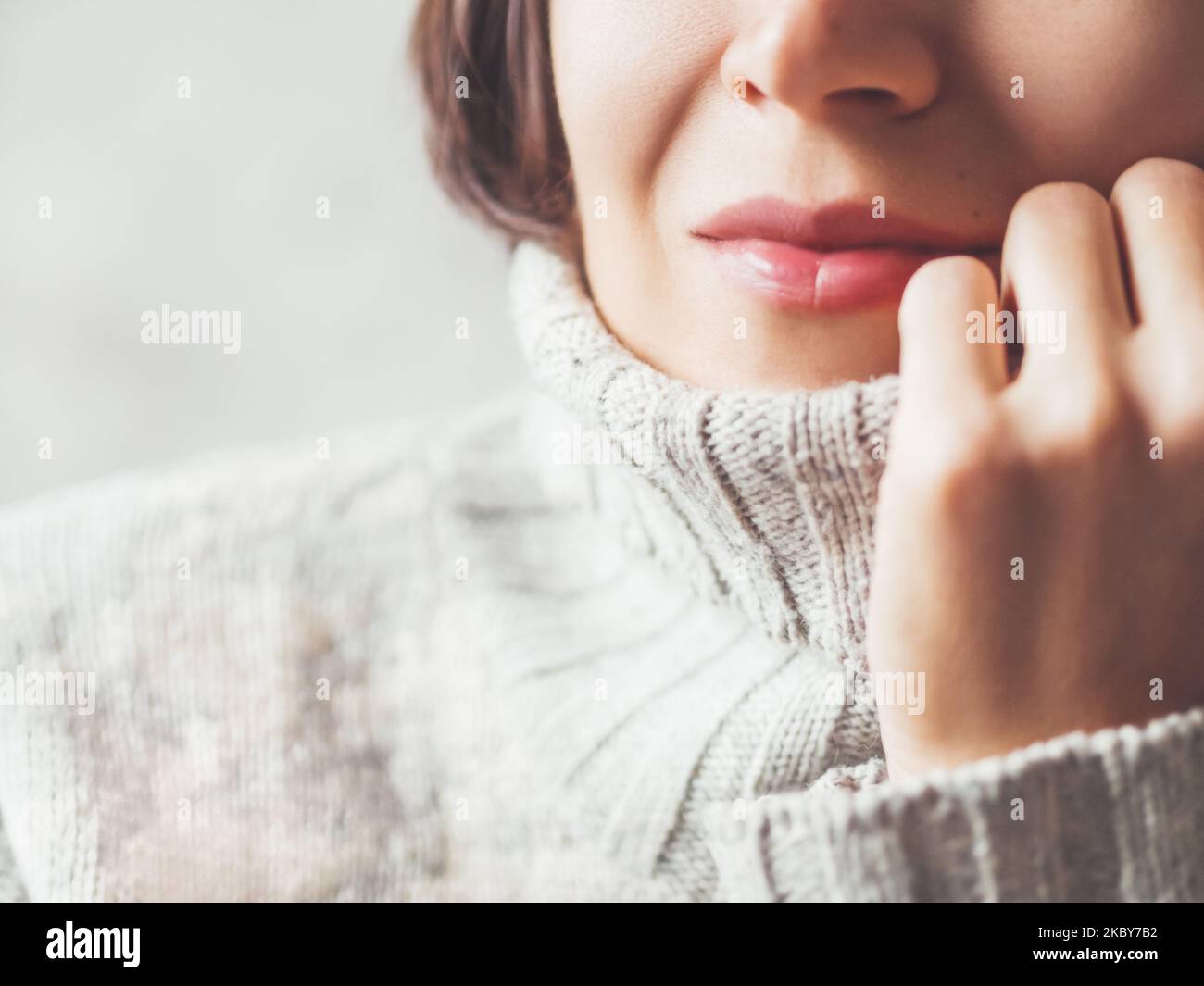 Nahaufnahme Porträt einer Frau kuscheln in warmen grauen Pullover. Lässiges Outfit für kaltes Wetter in der Wintersaison. Stockfoto