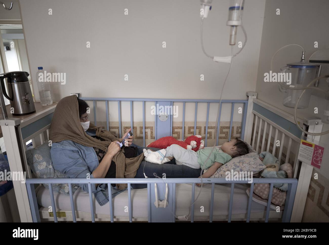 Die Mutter des 1 Monate alten Babys Aroosh, die von der neuen Coronavirus-Krankheit infiziert ist, setzt ihr Smartphone ein, während sie am 6. September 2020 auf ihrem Babykrankenhausbett im COVID-19-Bereich des Ali Asghar Kinderkrankenhauses im Norden Teherans sitzt. Die Iraner dachten, dass Kinder sich nicht mit dem COVID-19 infizieren würden, aber sie erkannten, dass Kinder jeden Alters mit der neuen Coronavirus-Krankheit infiziert werden, aber die meisten von ihnen, die infiziert sind, werden nicht so krank wie Erwachsene. (Foto von Morteza Nikoubazl/NurPhoto) Stockfoto