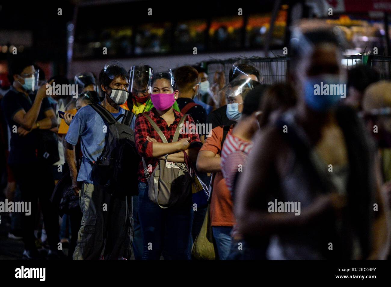 Pendler mit Gesichtsmasken und Gesichtsschutz stehen am 18. September 2020 an einem Busbahnhof in Quezon City, Philippinen, Schlange. (Foto: Lisa Marie David/NurPhoto) Stockfoto