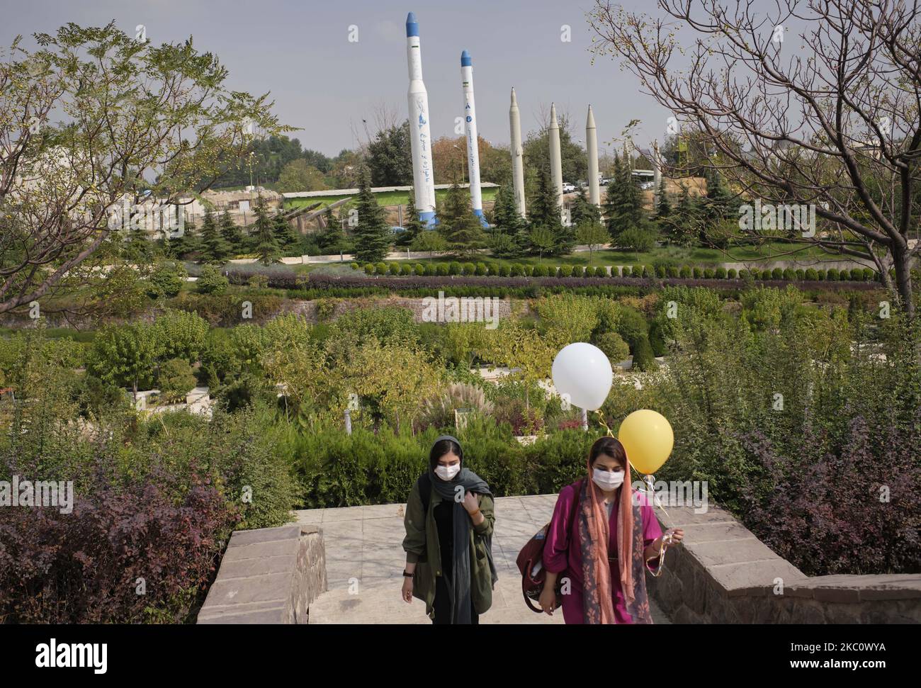 Zwei iranische Frauen, die eine von ihnen mit Luftballons auf einem Gebiet als Langstreckenraketen von der Oberfläche zur Oberfläche und zwei Satellitenträger (1. und 2. l) entlang laufen, werden im Garten-Museum der heiligen Verteidigung während einer Kriegsausstellung zum Gedenken an den Iran-Irak-Krieg (1980-88) am 29. September in Teheran ausgestellt. 2020. (Foto von Morteza Nikoubazl/NurPhoto) Stockfoto