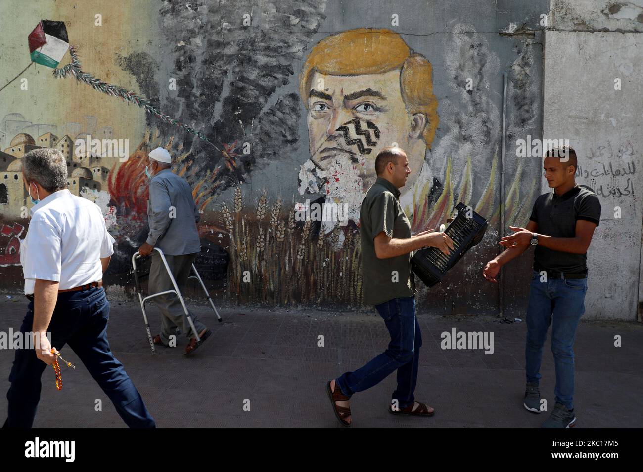 Palästinenser kommen am 5. Oktober 2020 an einem Wandgemälde vorbei, das US-Präsident Donald Trump mit einem Fußabdruck auf seinem Gesicht zeigt, auf einer Straße in Gaza-Stadt. (Foto von Majdi Fathi/NurPhoto) Stockfoto