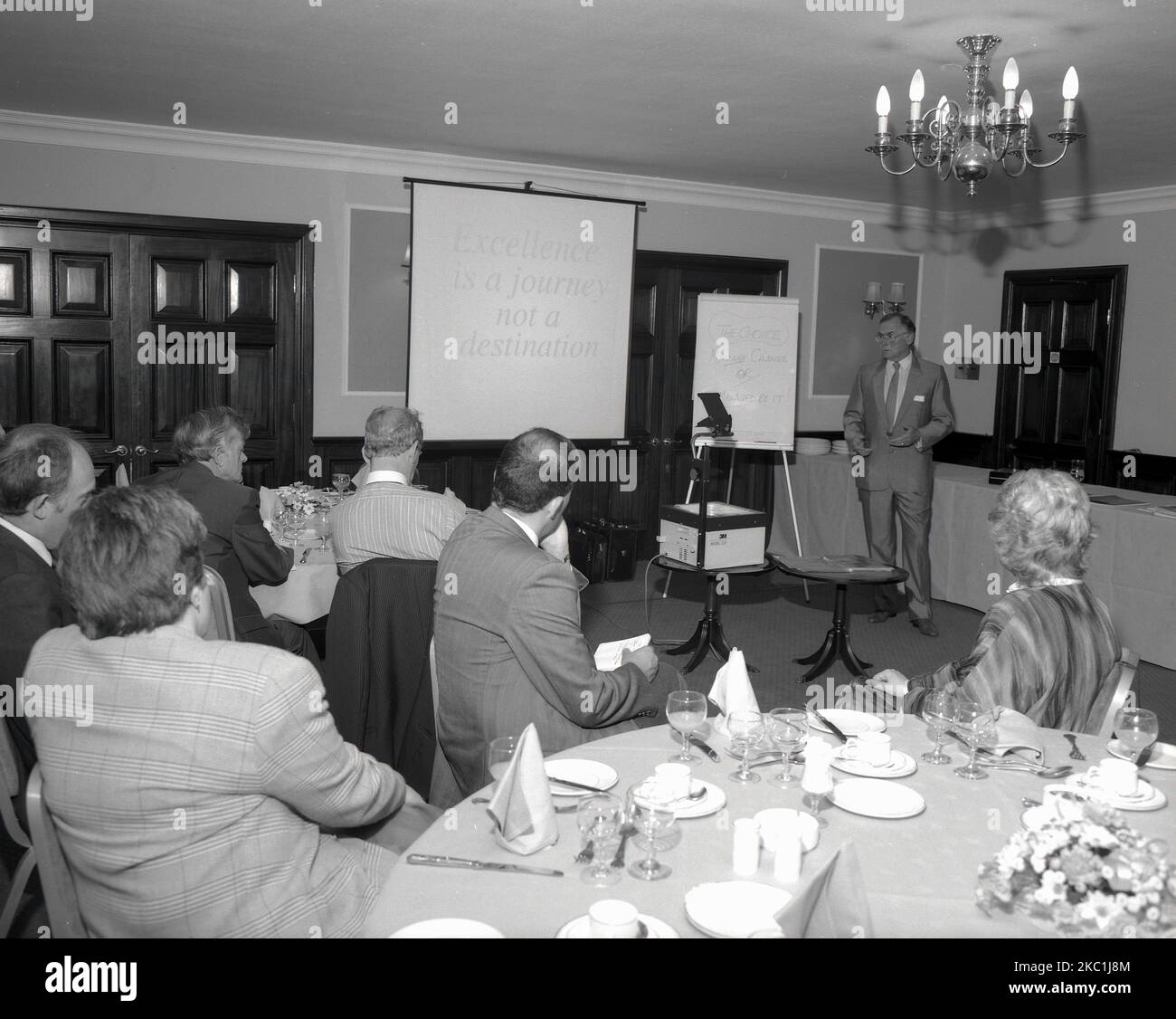 1980s, historische Managementschulung, in einem Konferenzraum des Hotels, mit Whiteboard und Overheadprojektor, ein Mann in einem Anzug, der eine Geschäftspräsentation vor einigen Führungskräften des Unternehmens vorstellte, England, Großbritannien. Stockfoto