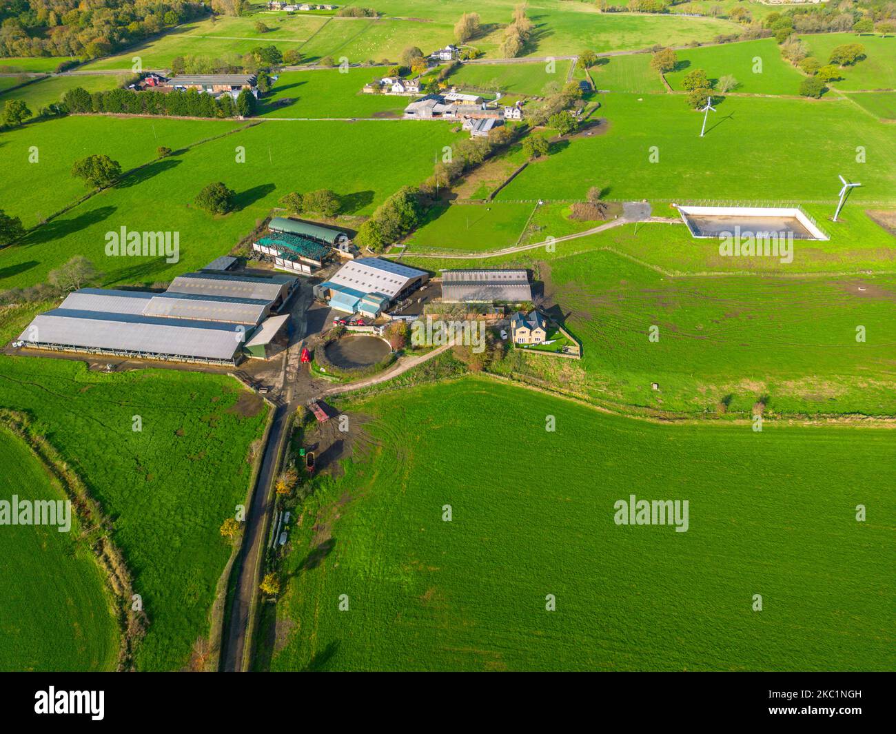 Luftaufnahme eines landwirtschaftlichen Betriebs mit zwei Windkraftanlagen für erneuerbare, saubere Energie in der Landschaft von North Yorkshire im Vereinigten Königreich. Stockfoto