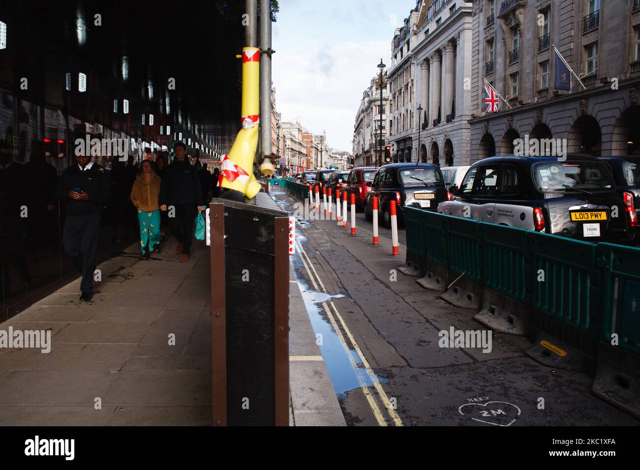 Am 15. Oktober 2020 steht an der Piccadilly in London, England, neben einem ungenutzten, vorübergehend ausgebauten Straßenbelag, der zur Unterstützung der sozialen Distanzierung dienen soll, eine Staus. London wird ab diesem Wochenende unter die „Tier 2“-Coronavirus-Sperrmaßnahmen fallen, die ein Verbot für Menschen aus verschiedenen Haushalten einführen werden, überall in Innenräumen zu mischen, was besondere Sorge für die bereits stark betroffene Hotellerie bedeutet. In mehreren anderen Teilen des Landes sollen auch die Covid-19-Beschränkungen ähnlich verschärft werden. Das dreistufige System für England trat diese Woche in Kraft, mit jedem Bereich Stockfoto