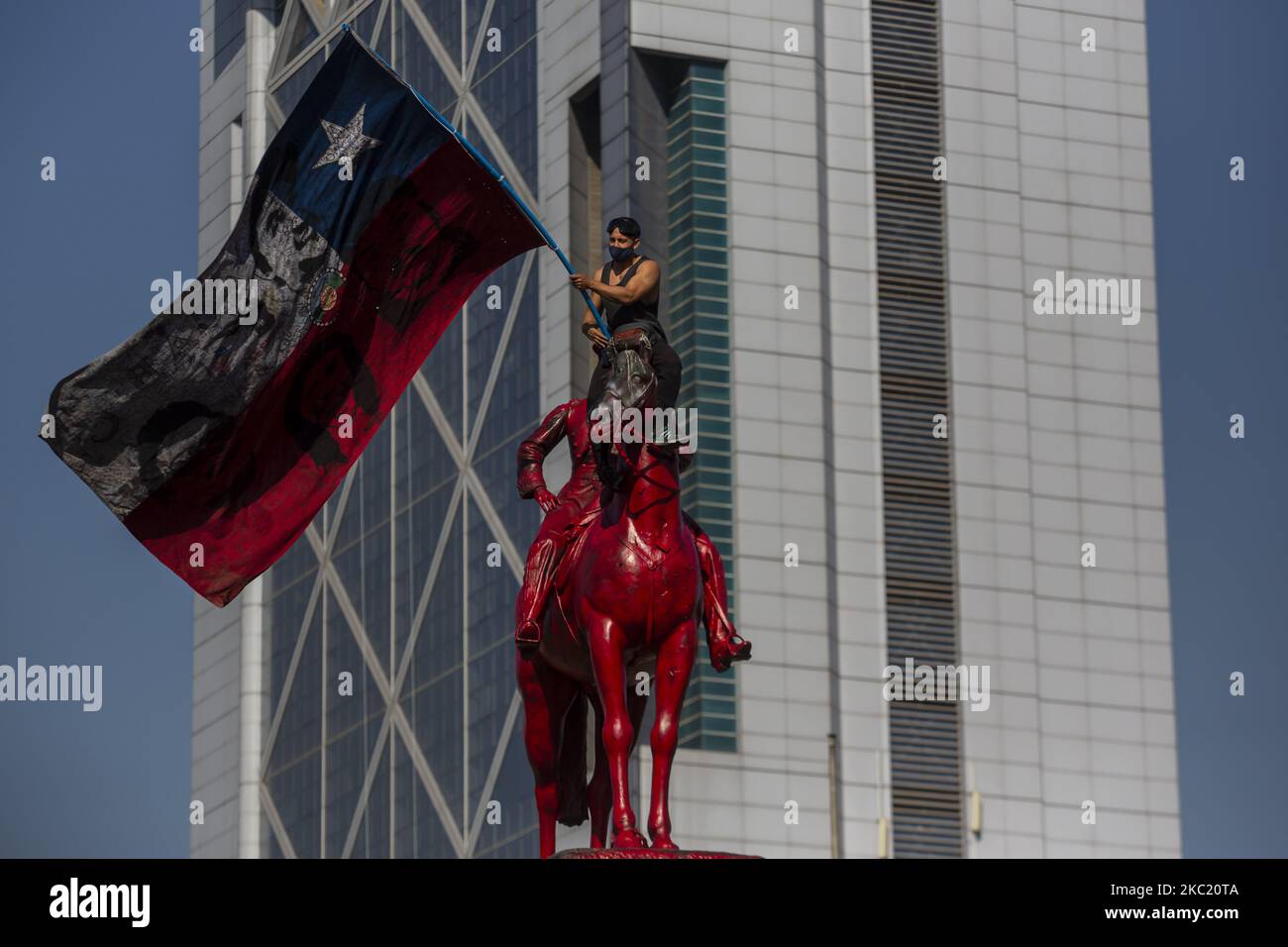 Eine Person hält eine chilenische Flagge auf der Statue auf der Plaza Dignidad. Inmitten der Demonstration und des Protests gegen die Regierung von Sebastián Piñera, soziale Ungleichheit und das neoliberale System. Am 16. Oktober 2020 in Santiago de Chile, Chile. (Foto von Claudio Abarca Sandoval/NurPhoto) Stockfoto