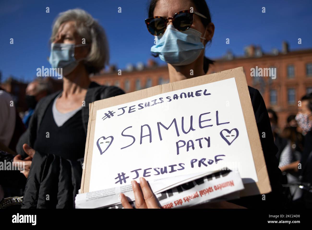 Eine Frau hält ein Plakat mit der Aufschrift 'Ich bin Samuel Paty, #Imateacher'. Mit einem Band in den französischen Farben. Nach der Tötung von Samuel Paty, Lehrer für Geographie-Geschichte, in Conflans-Sainte-Honorine (Yvelines) am 16.. Oktober versammelten sich mehrere Tausende von Menschen auf dem Hauptplatz von Toulouse, vor dem Rathaus, dem Capitole, um die Meinungsfreiheit zu verteidigen und Samuel zu ehren. Einige Leute kamen mit einem Cover von Charlie Hebdo, da der Lehrer getötet wurde, nachdem er seinen Schülern die Karikaturen von Charlie Hebdo von Muhammed gezeigt hatte. Der Mörder wurde anschließend von der französischen Polizei getötet. Ein Stockfoto